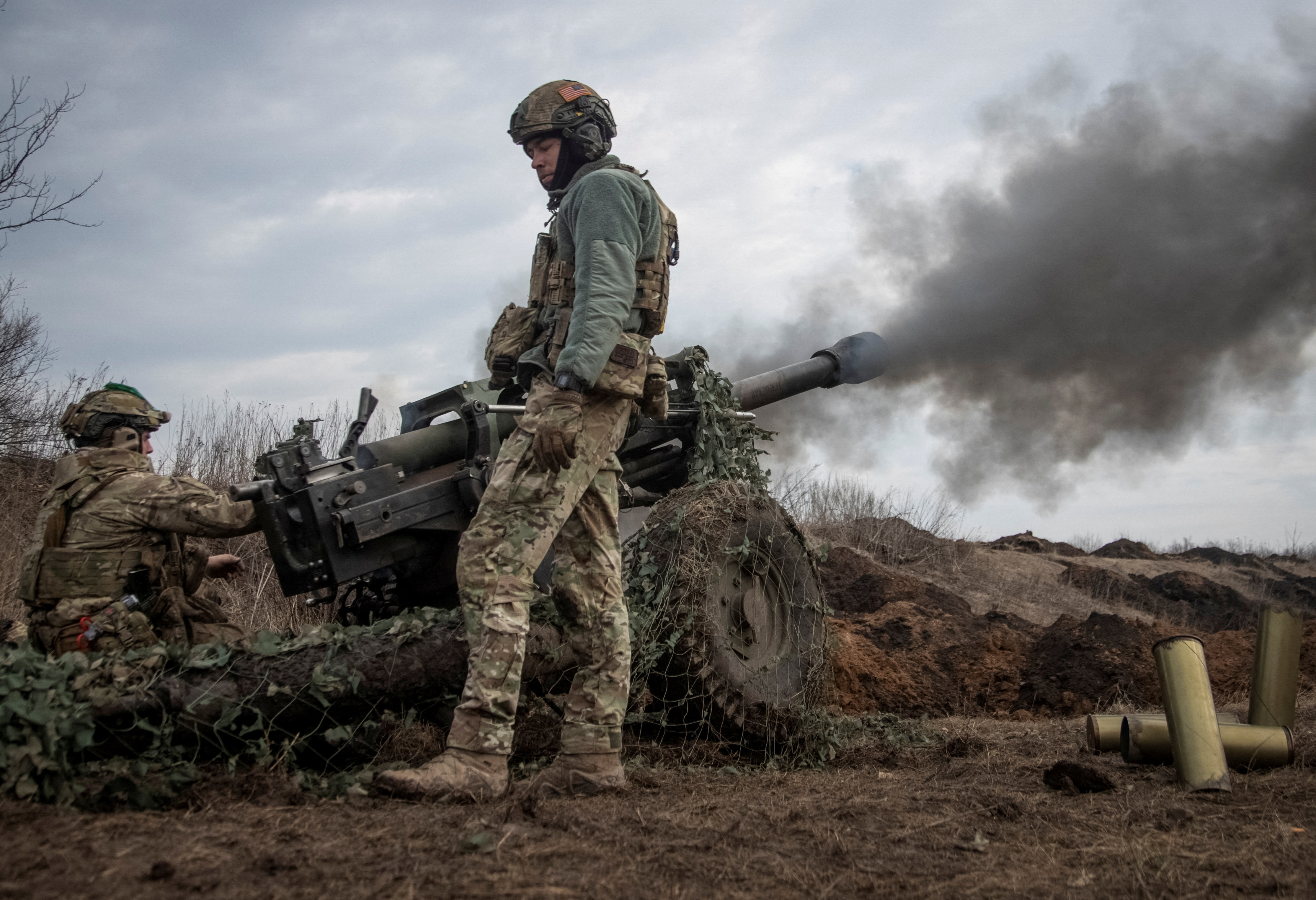 Ukrainian service members fire a howitzer M119 at a front line near Bakhmut