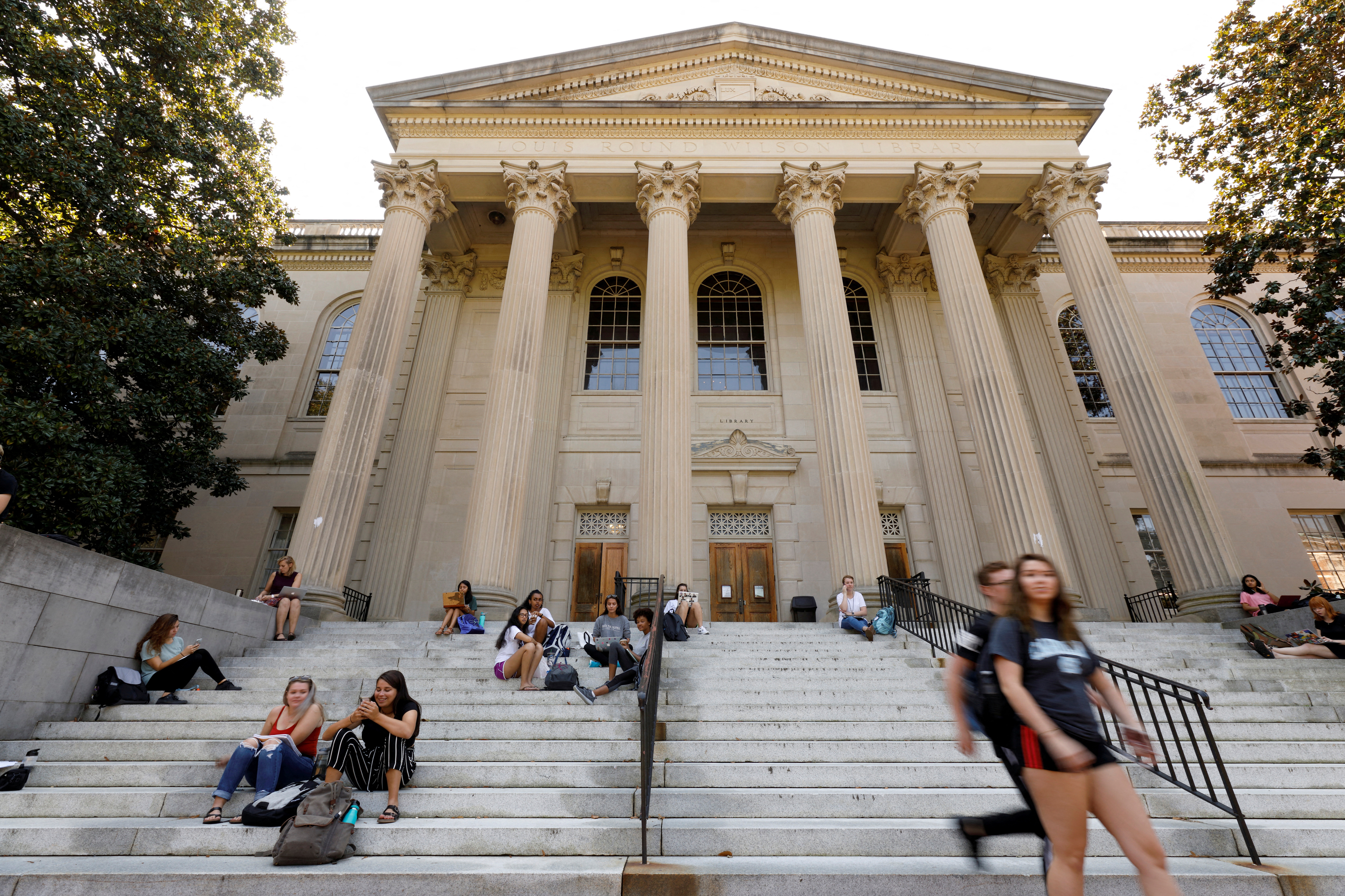 Students sit on the steps of Wilson Library on the campus of University of North Carolina at Chapel Hill North Carolina