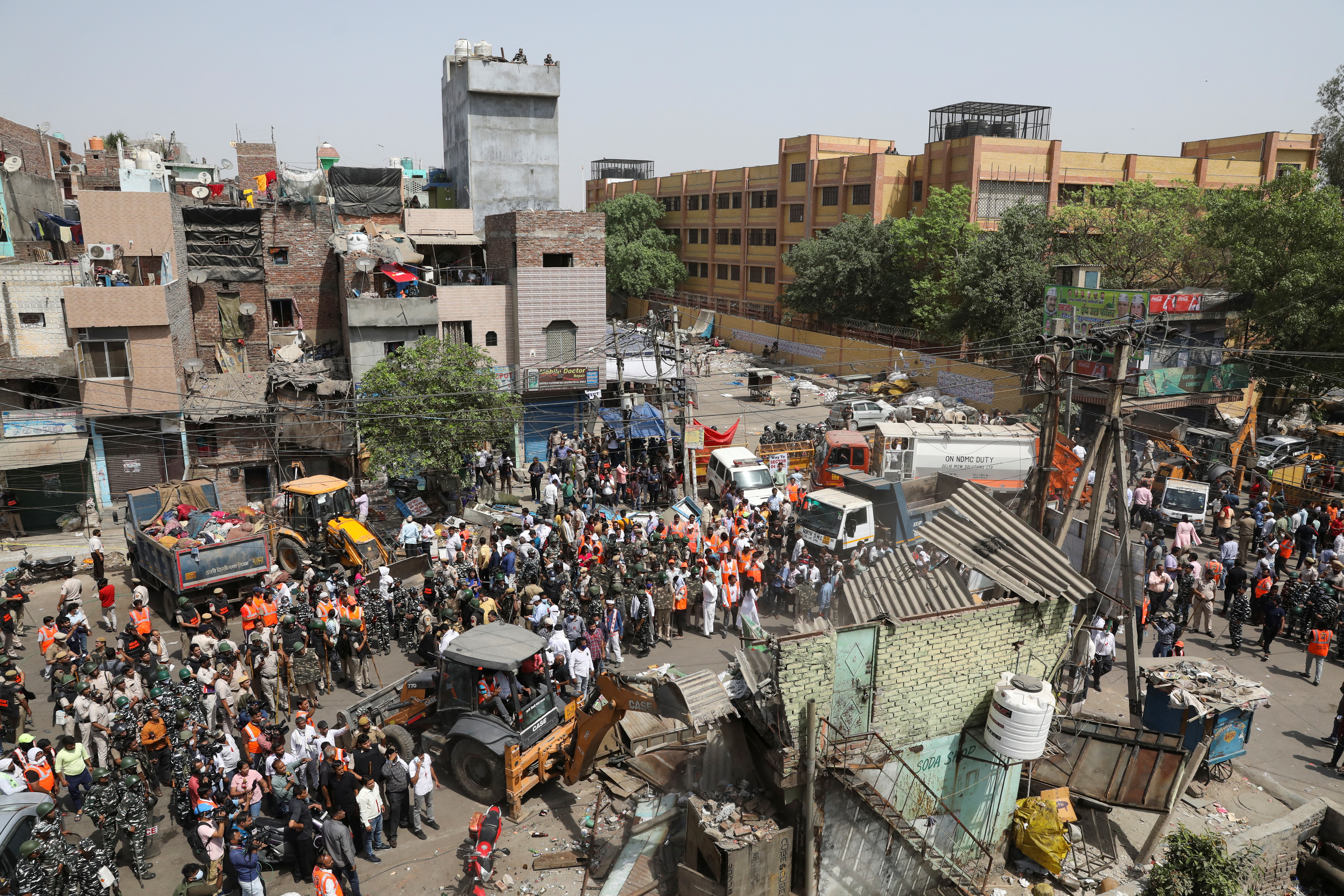 Police officials and members of security forces oversee the demolition of small illegal retail shops, in New Delhi