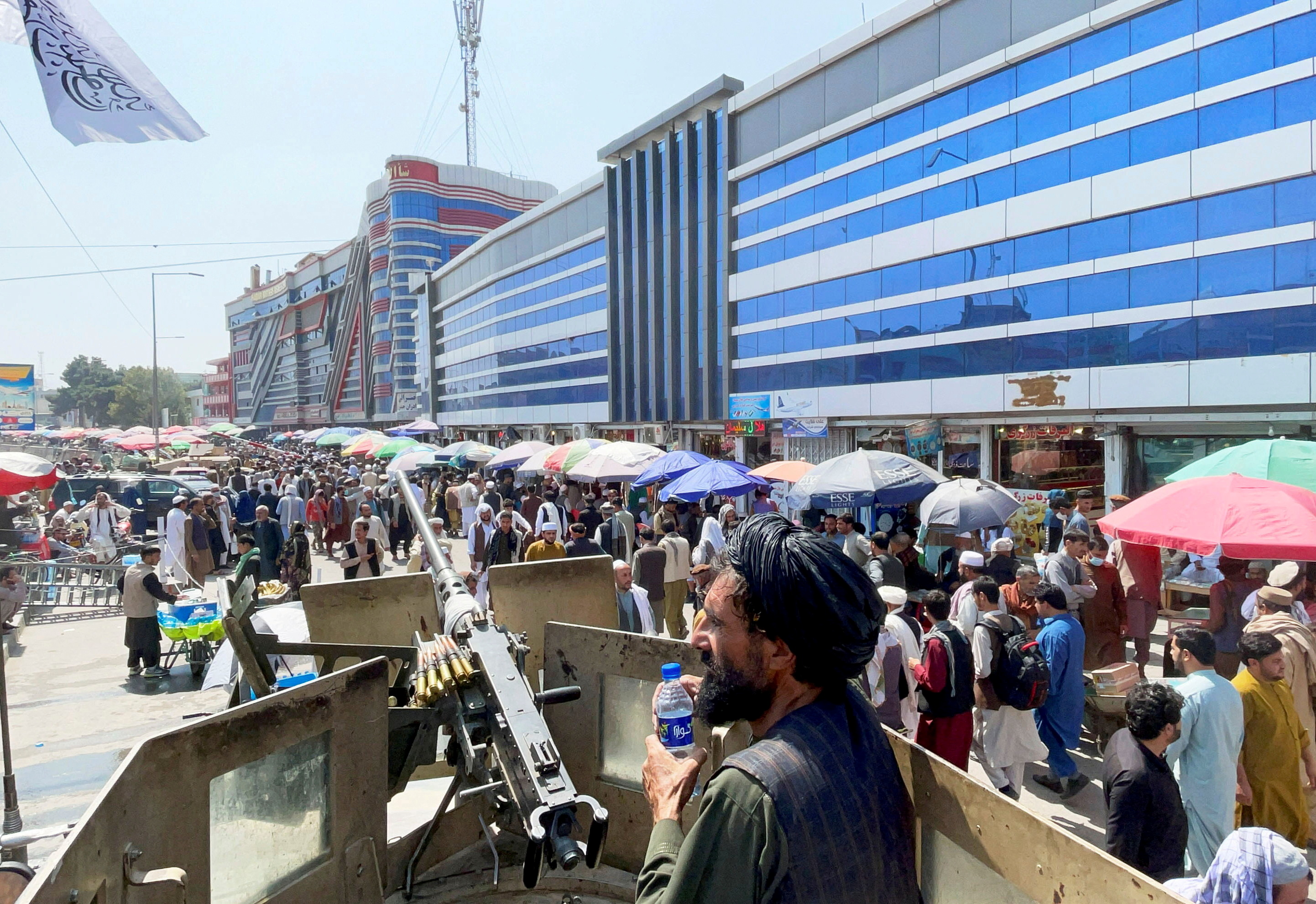 Taliban security forces stand guard among crowds of people in front of money exchange market in Kabul