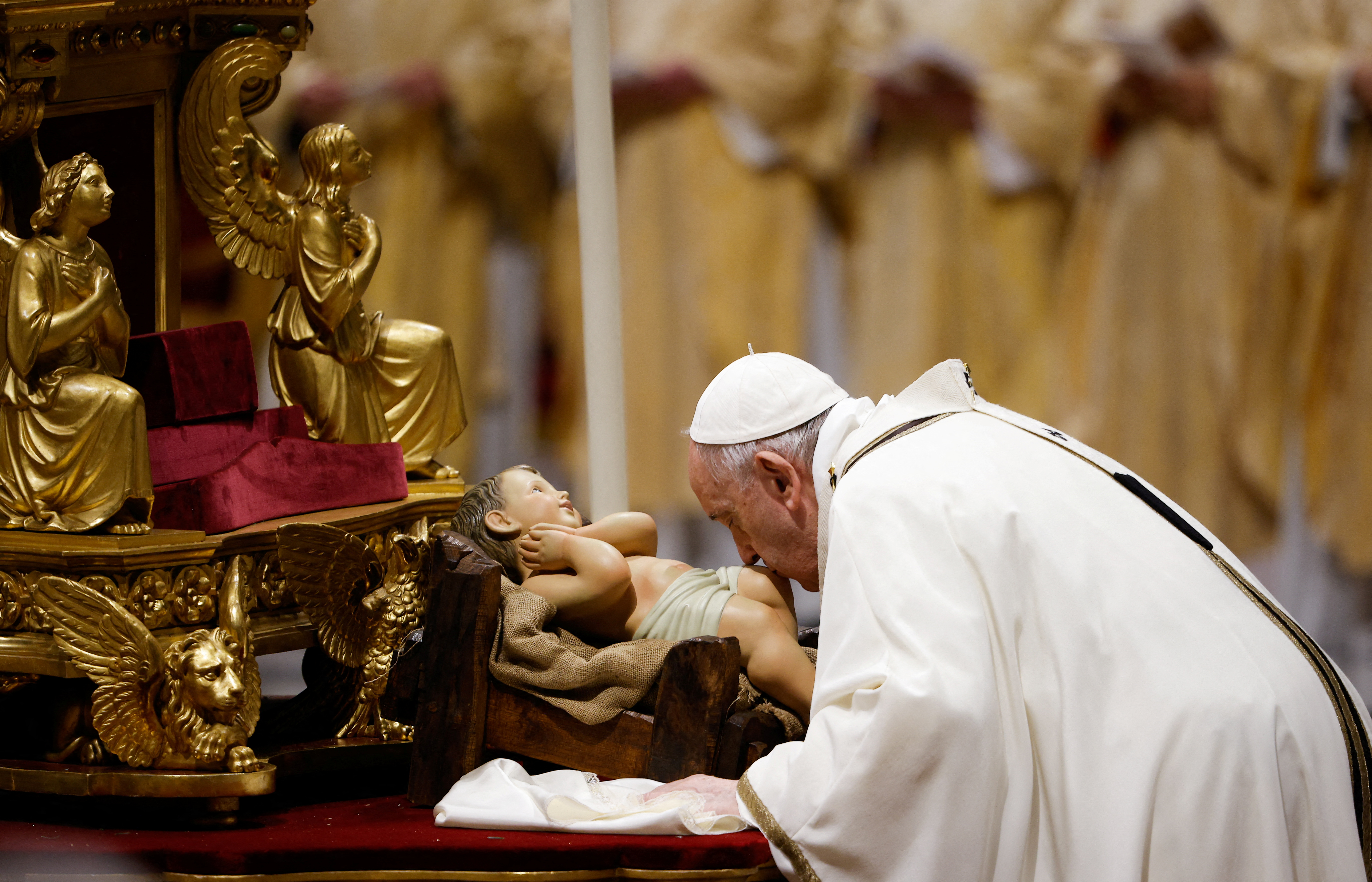Pope Francis kisses a statue of baby Jesus as he celebrates Christmas Eve Holy Mass in St. Peter's Basilica at the Vatican, December 24, 2021. REUTERS/Guglielmo Mangiapane