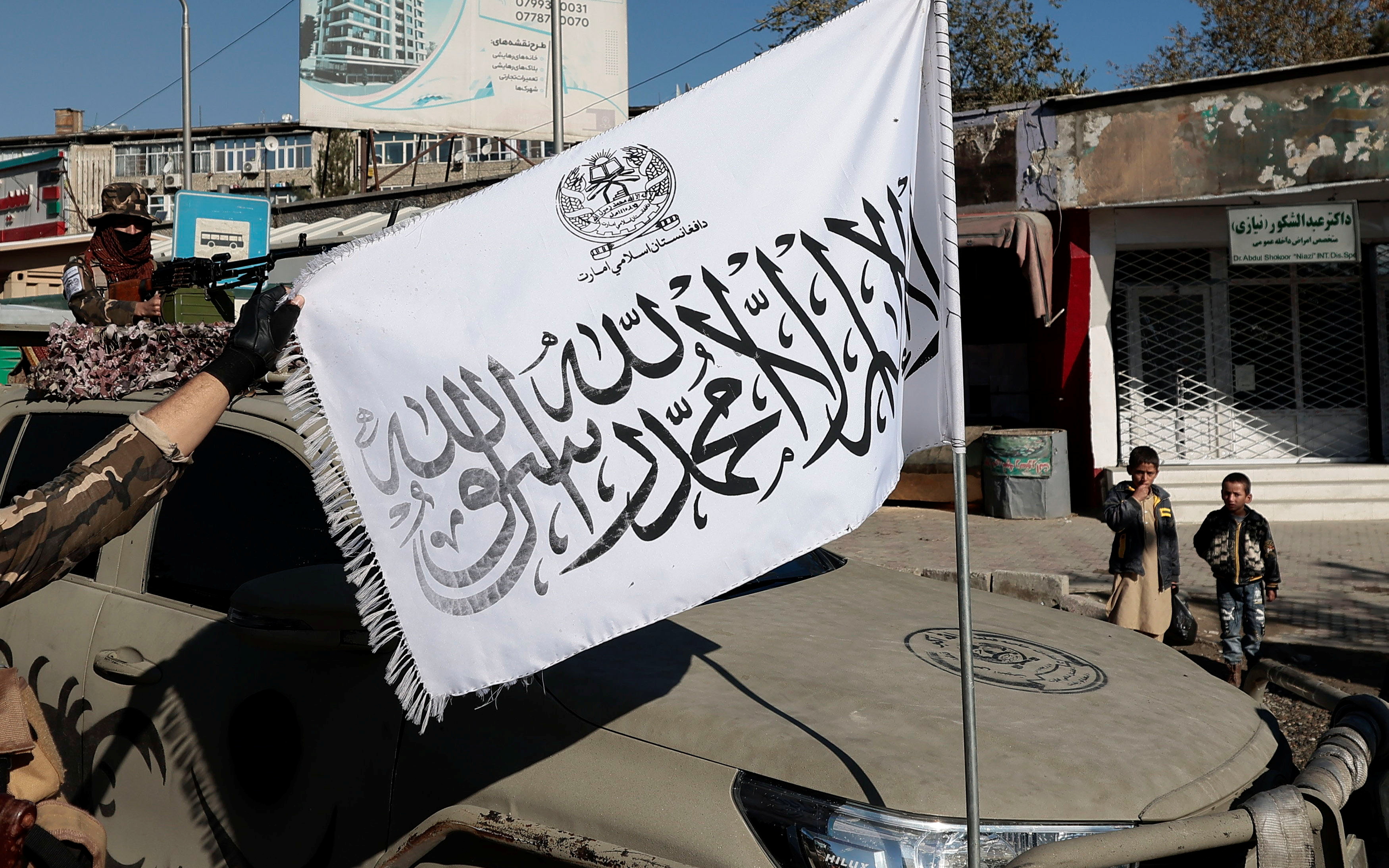 A Taliban fighter displays their flag as his comrade watches, at a checkpoint in Kabul, Afghanistan November 5, 2021. REUTERS/Zohra Bensemra