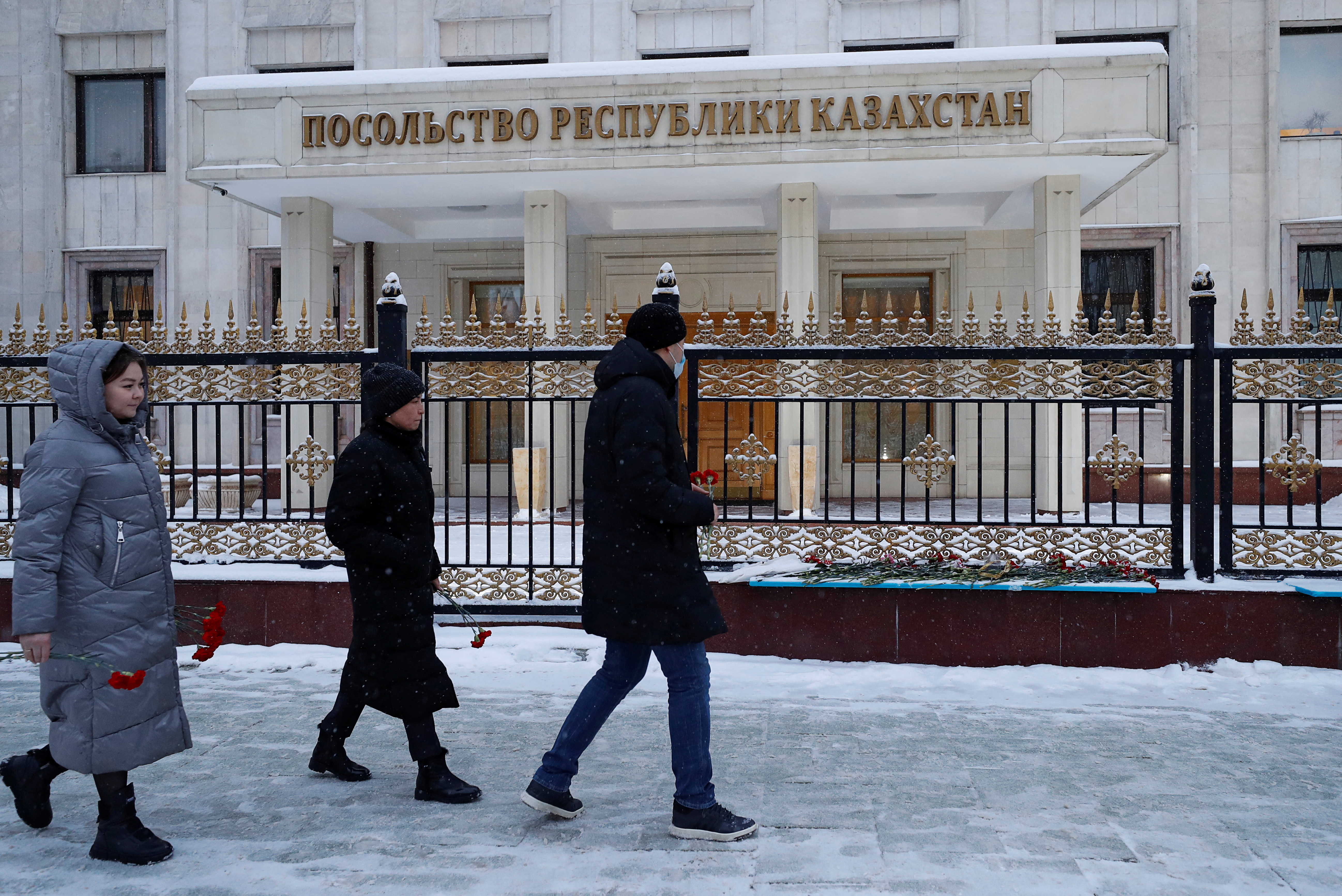 People walk to place flowers outside the Kazakh Embassy in Moscow