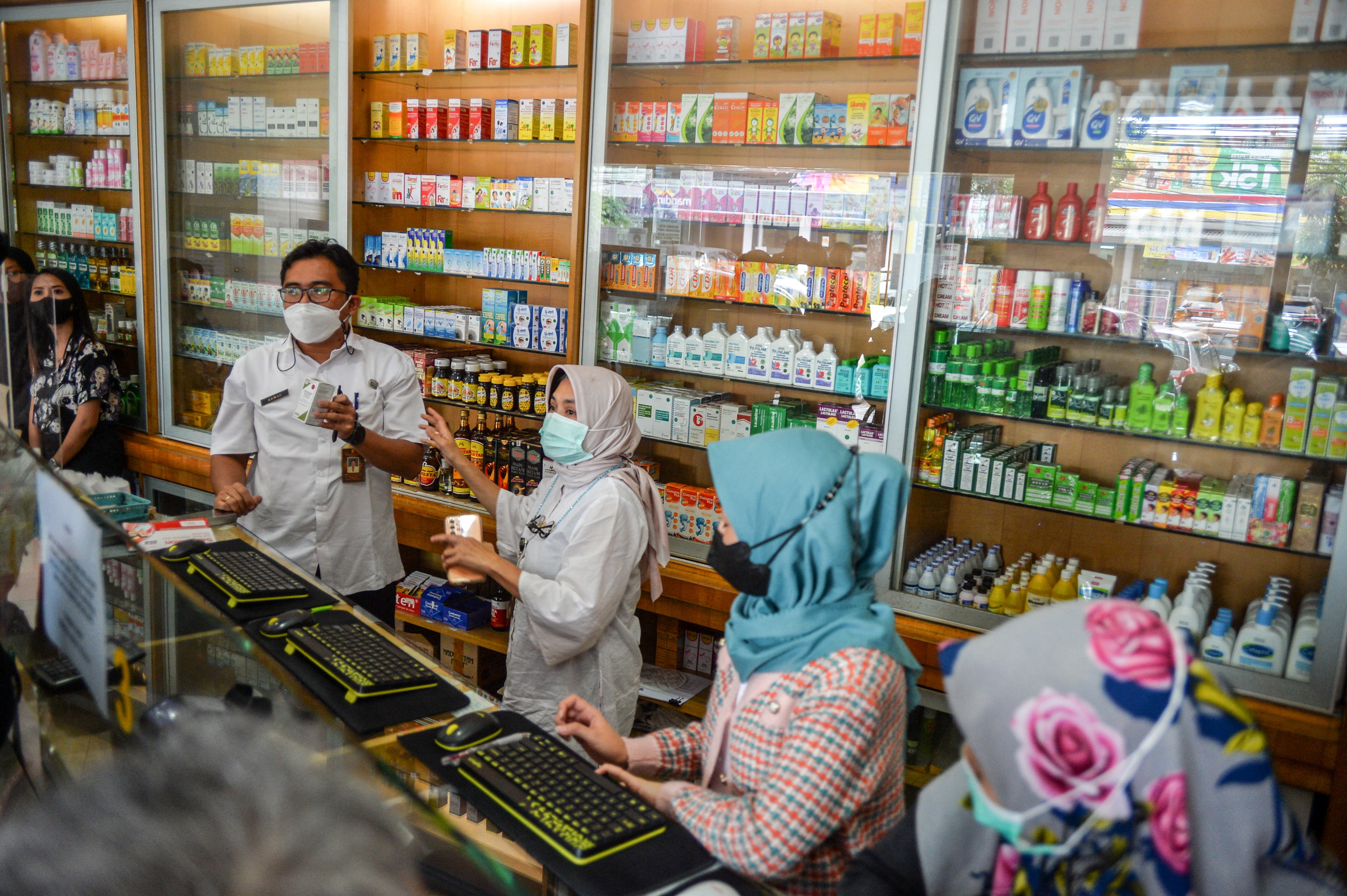 Health officers inspect medicinal syrups containing ethylene glycol and diethylene glycol at a pharmacy in Bandung