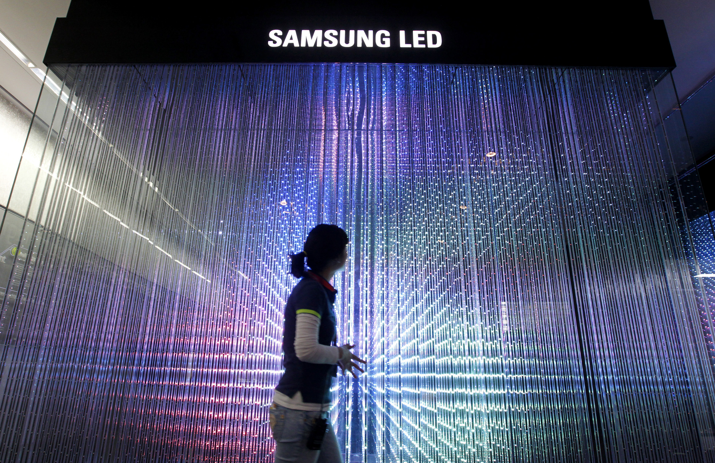 An employee of Samsung Electronics walks past LED lighting drums displayed for visitors at a showroom in Seoul
