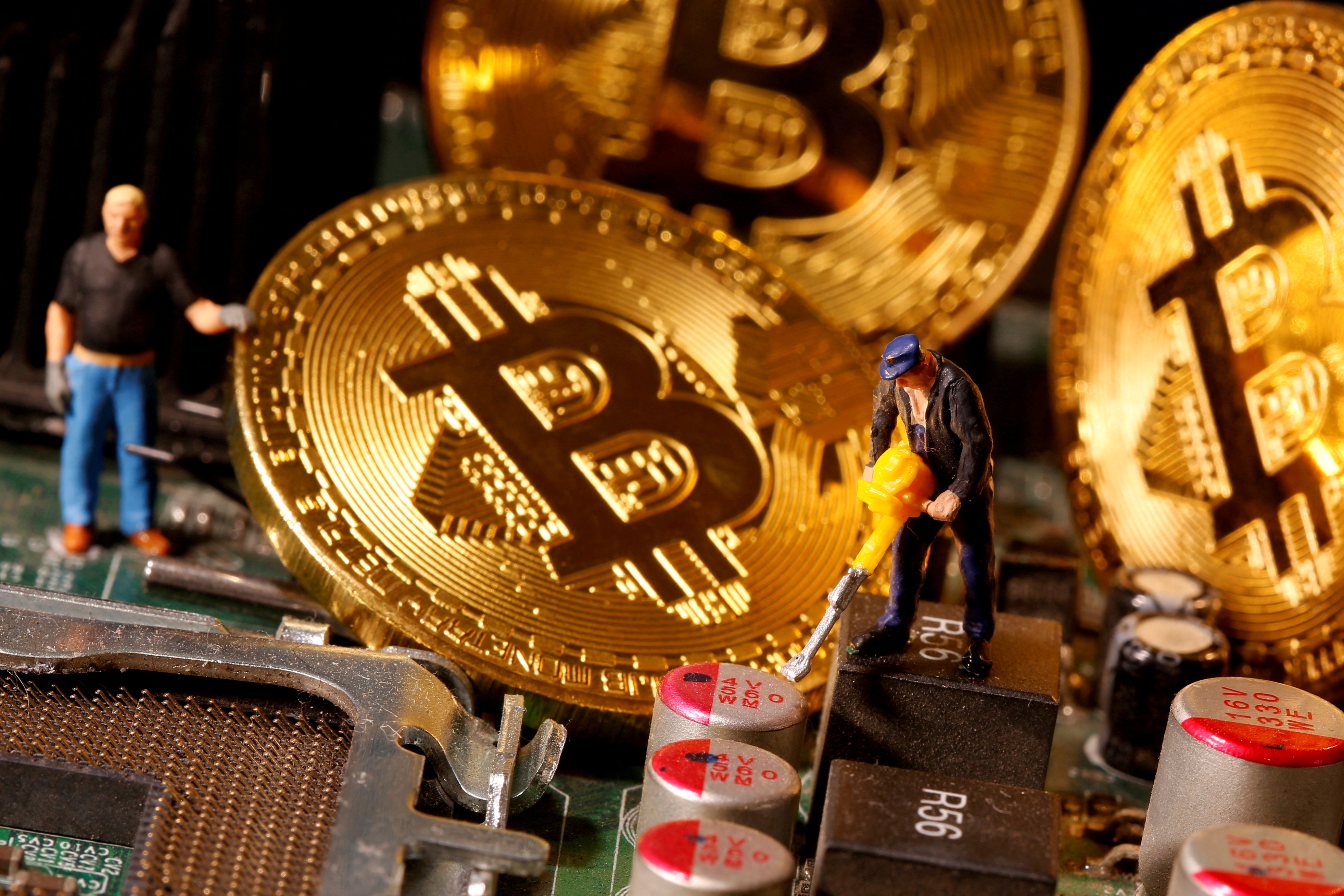 A representation of virtual currency Bitcoin and small toy figures are placed on computer motherboard