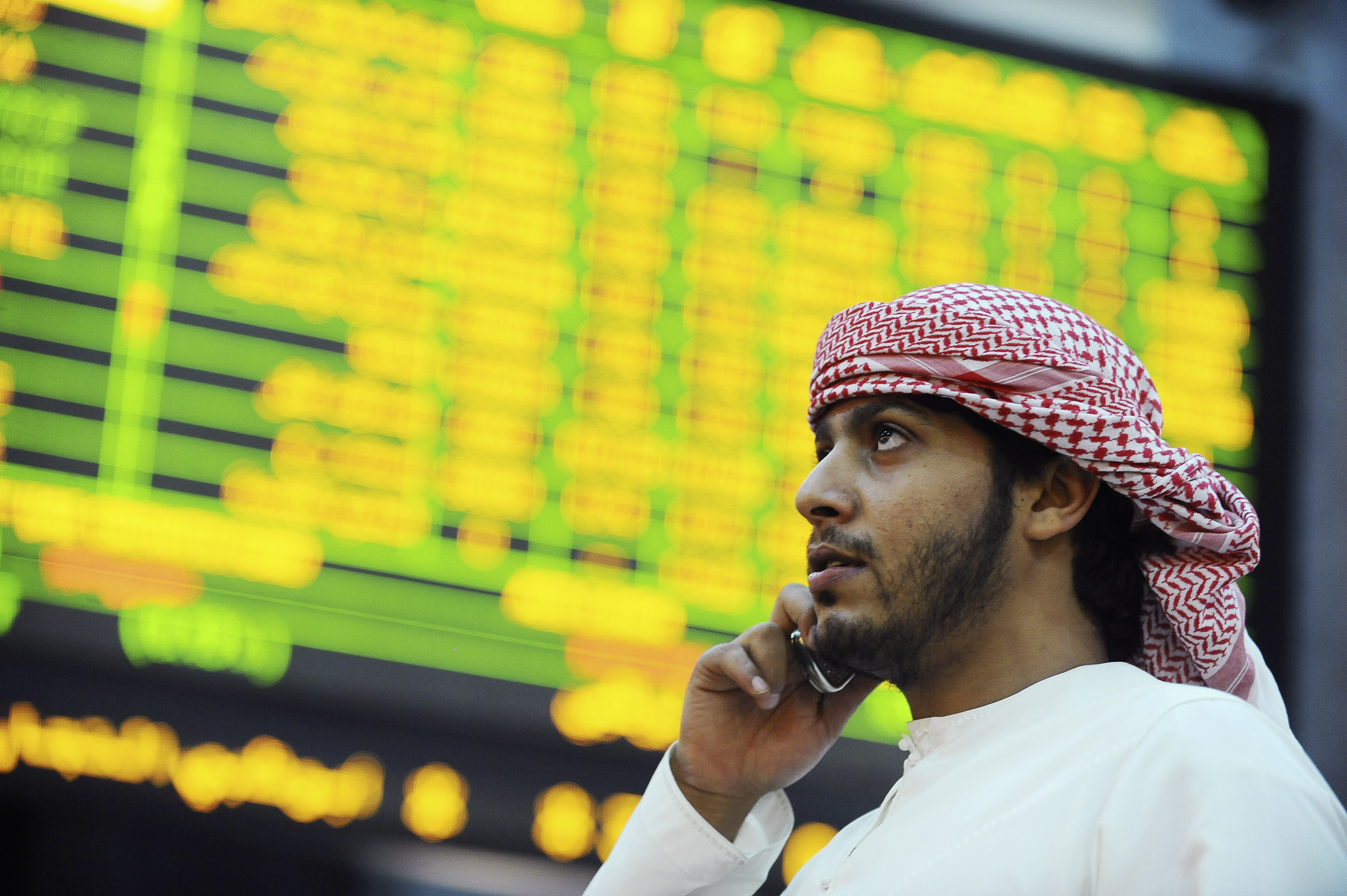 An investor looks up at electronic boards displaying stock information at the ADX Abu Dhabi Securities Exchange stock market