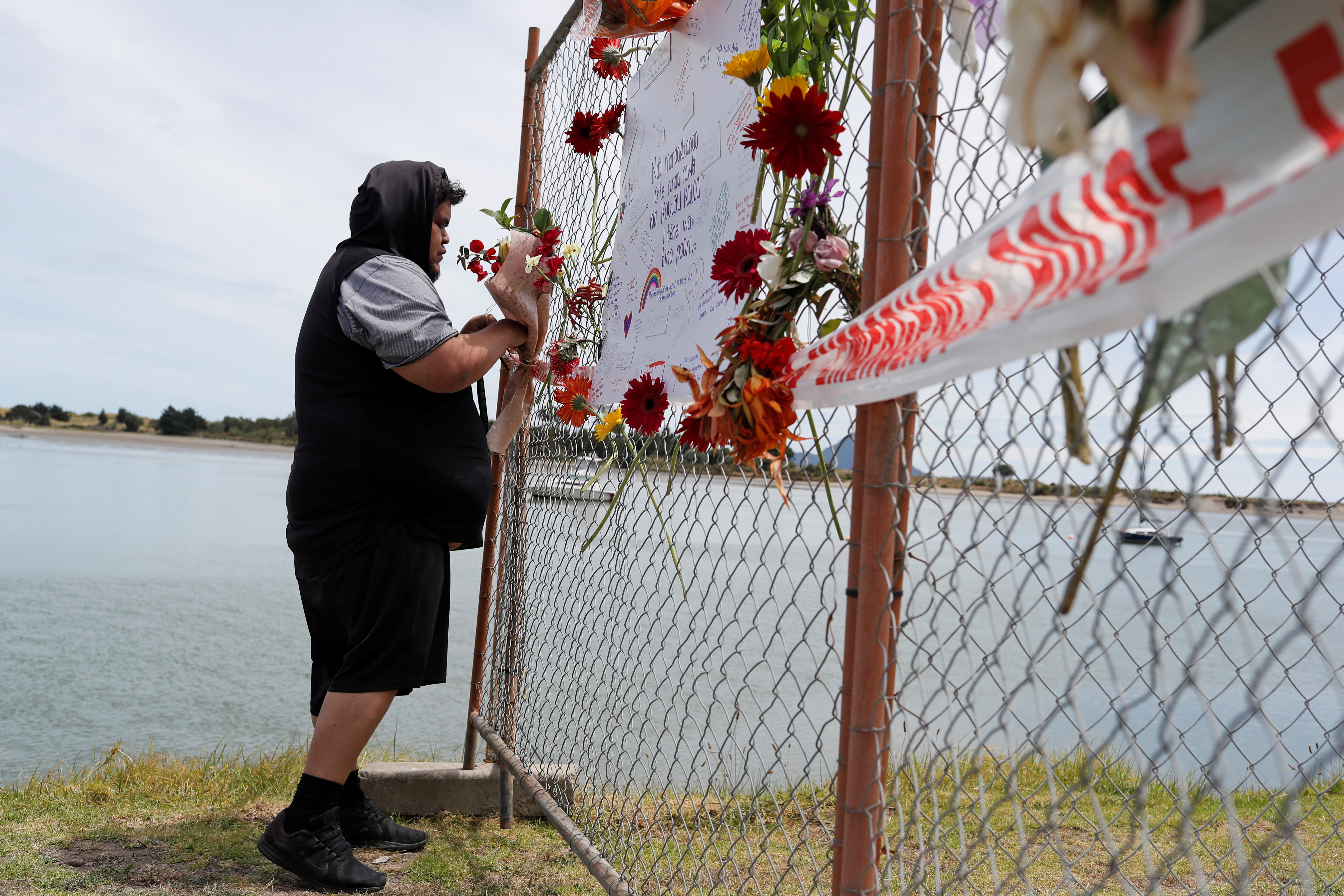 A man offers flowers at a memorial at the harbour in Whakatane, following the White Island volcano eruption in New Zealand