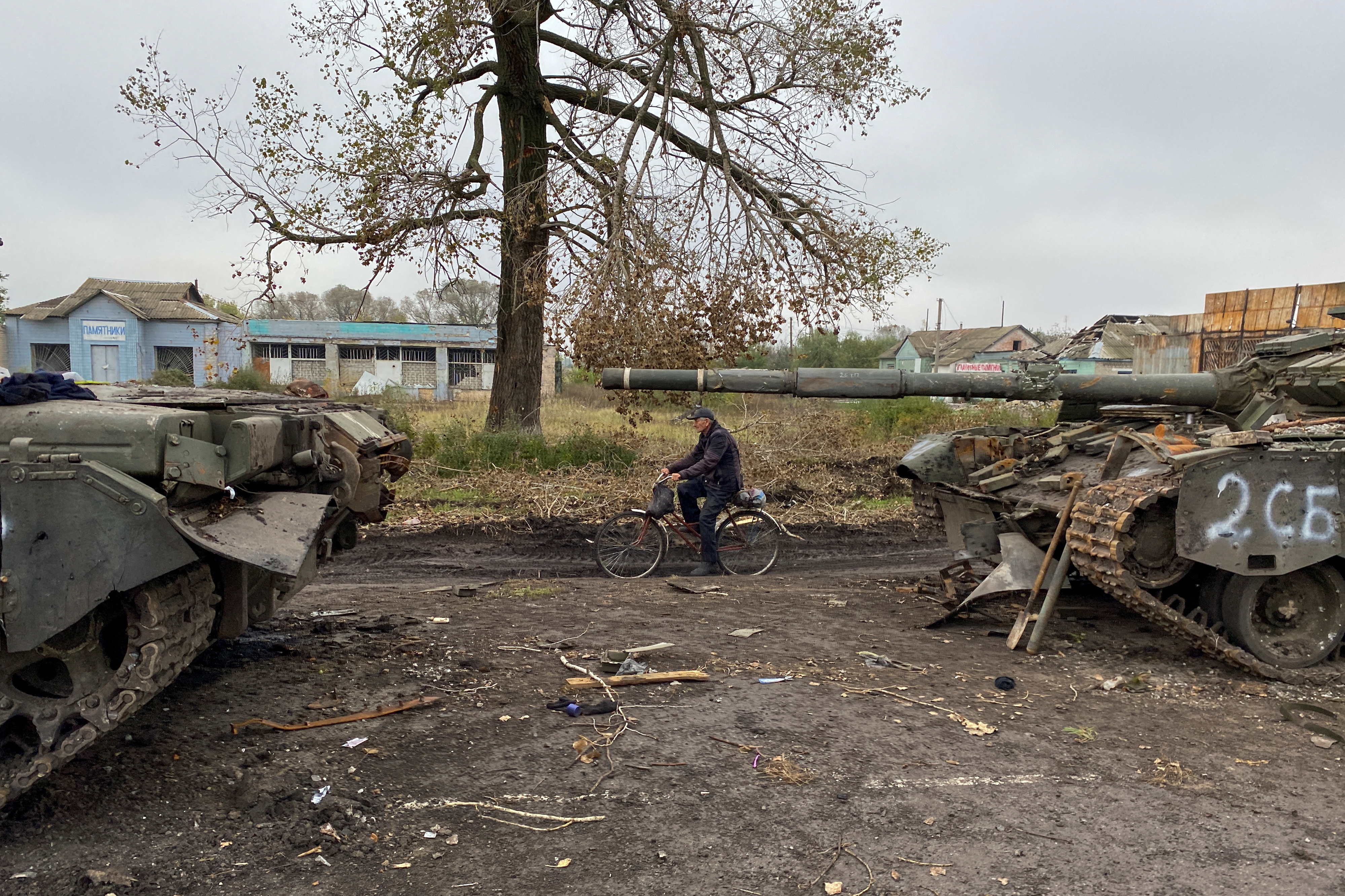 FILE PHOTO - Local resident rides a bicycle past abandoned Russian tanks in the village of Kurylivka