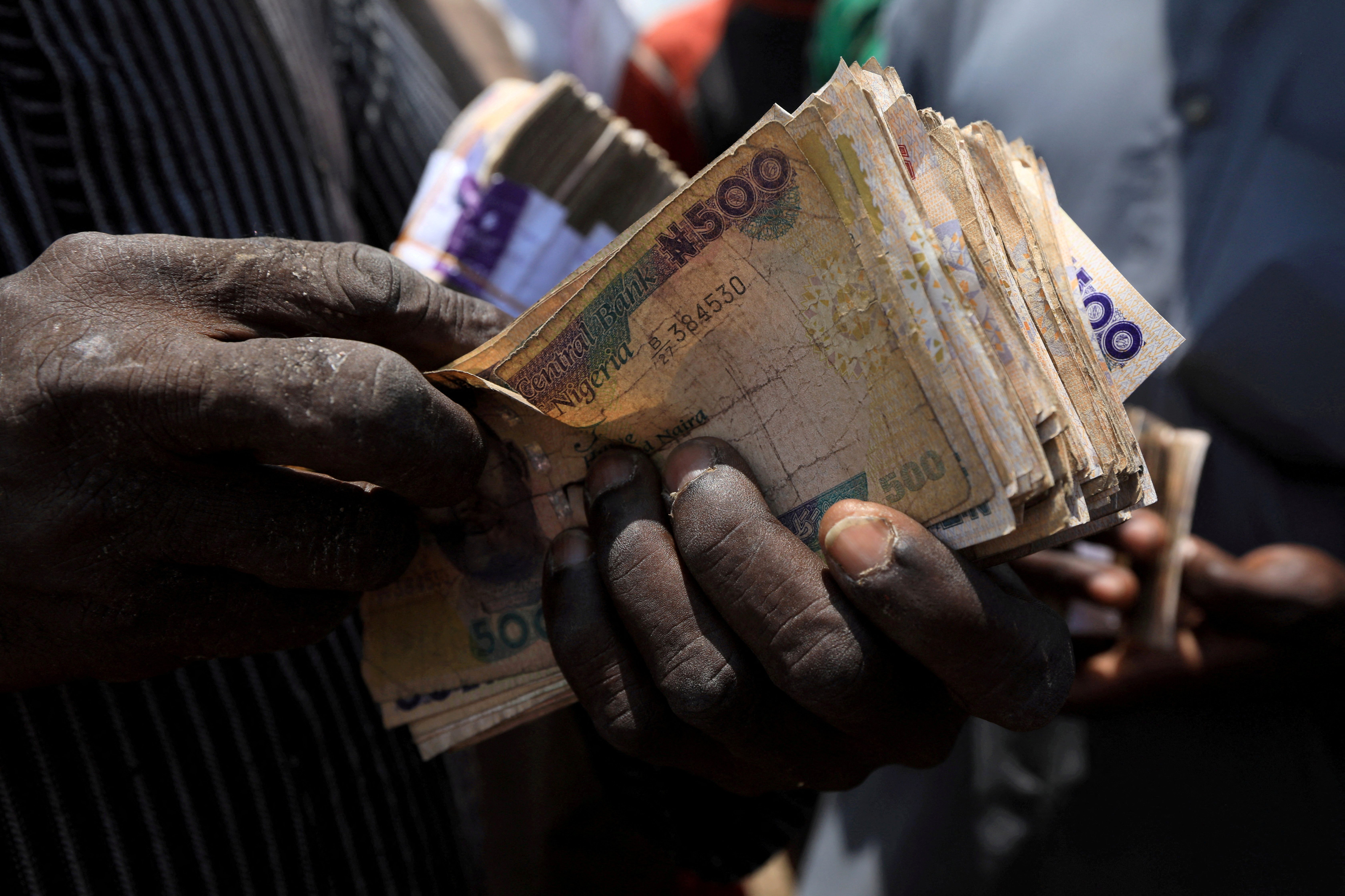 Man carries Nigerian naira banknotes at a livestock market in Abuja