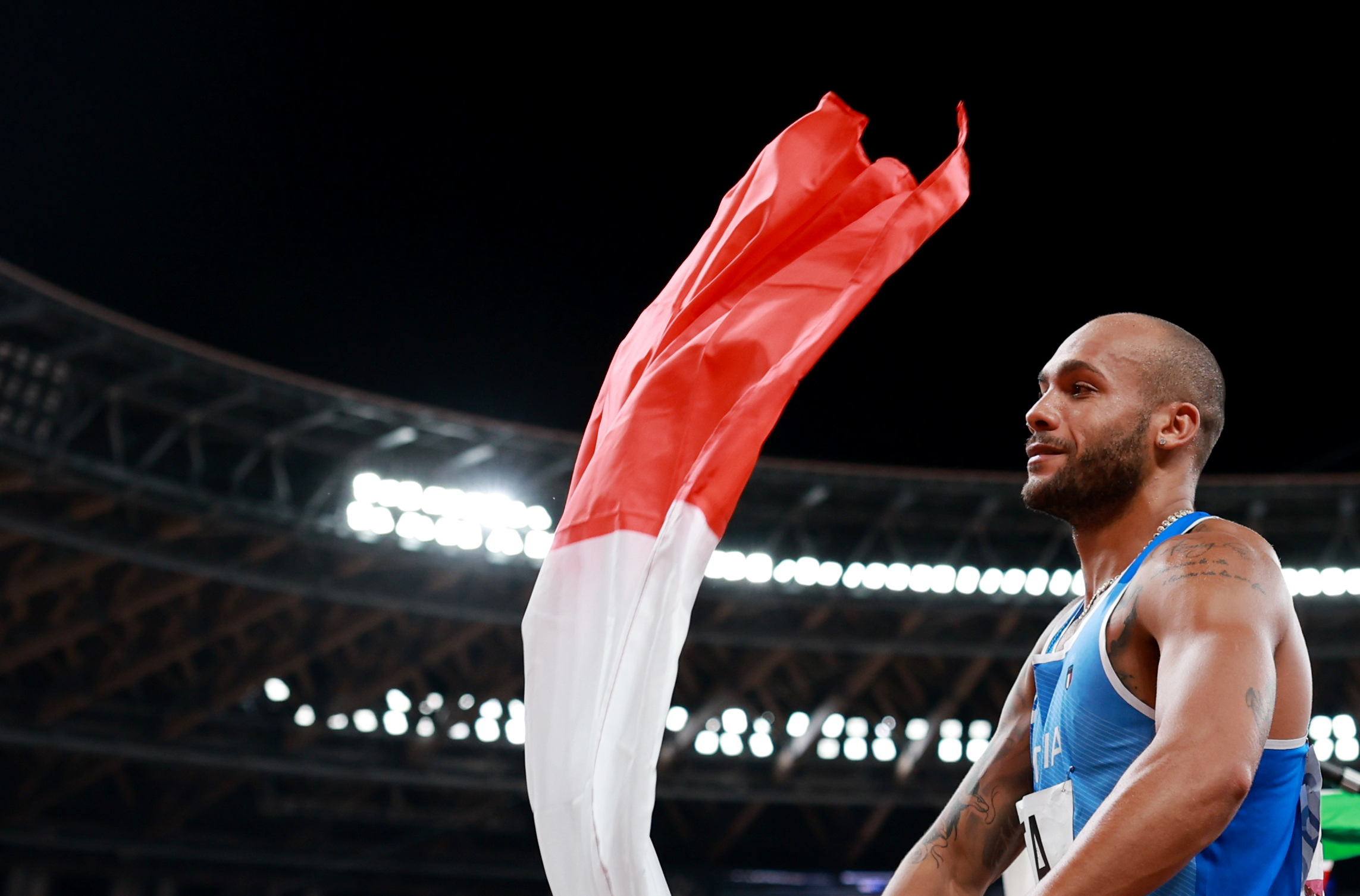 Tokyo 2020 Olympics - Athletics - Men's 4 x 100m Relay - Final - Olympic Stadium, Tokyo, Japan - August 6, 2021. Lamont Marcell Jacobs of Italy celebrates with his national flag after winning gold REUTERS/Kai Pfaffenbach