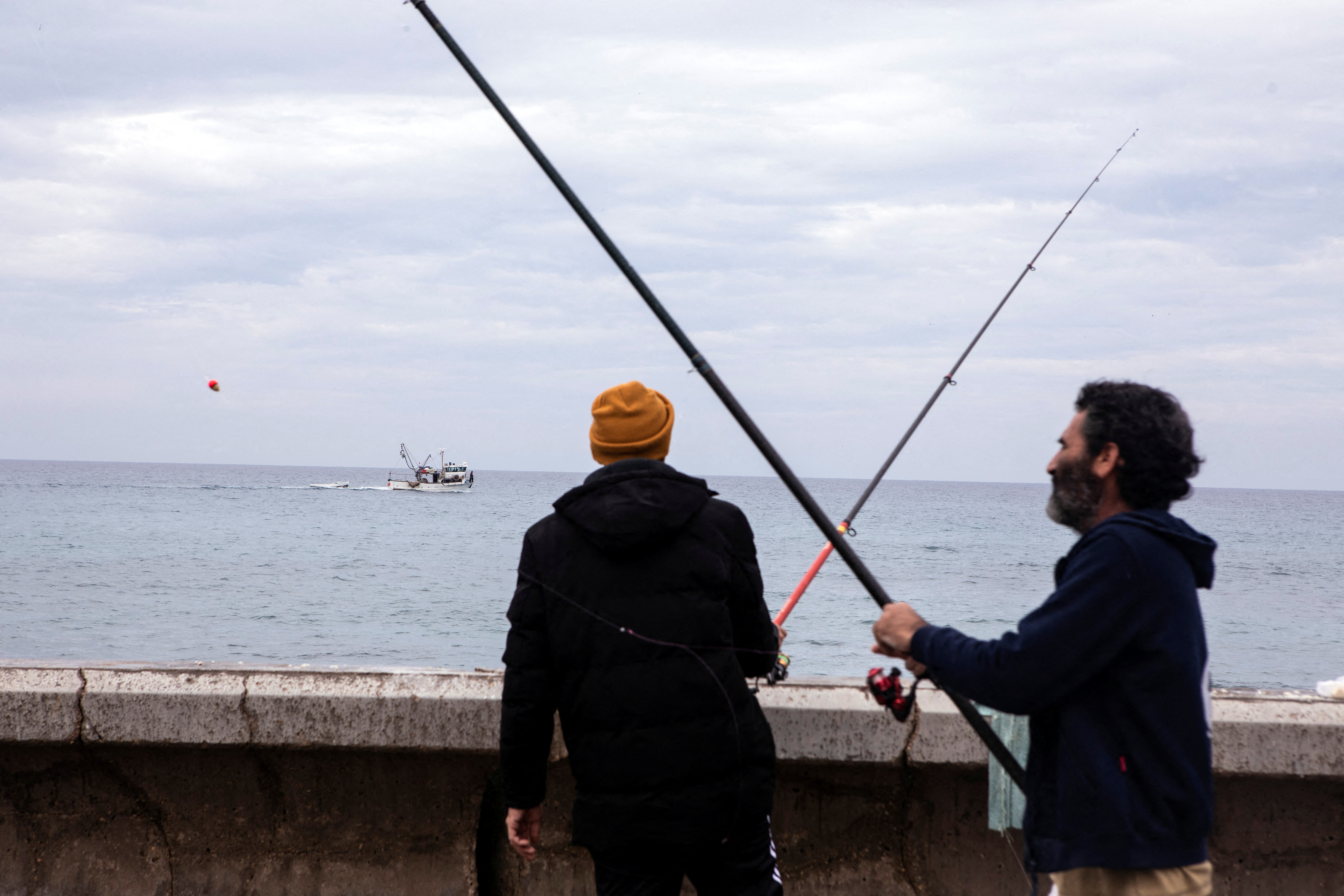 I pescatori israeliani si trovano sulla riva del Mediterraneo dopo che i razzi lanciati da militanti palestinesi a Gaza hanno causato un'esplosione al largo di una spiaggia di Tel Aviv, secondo le forze di difesa israeliane, a Tel Aviv, Israele, 1 gennaio 2022. REUTERS/Nir Elias