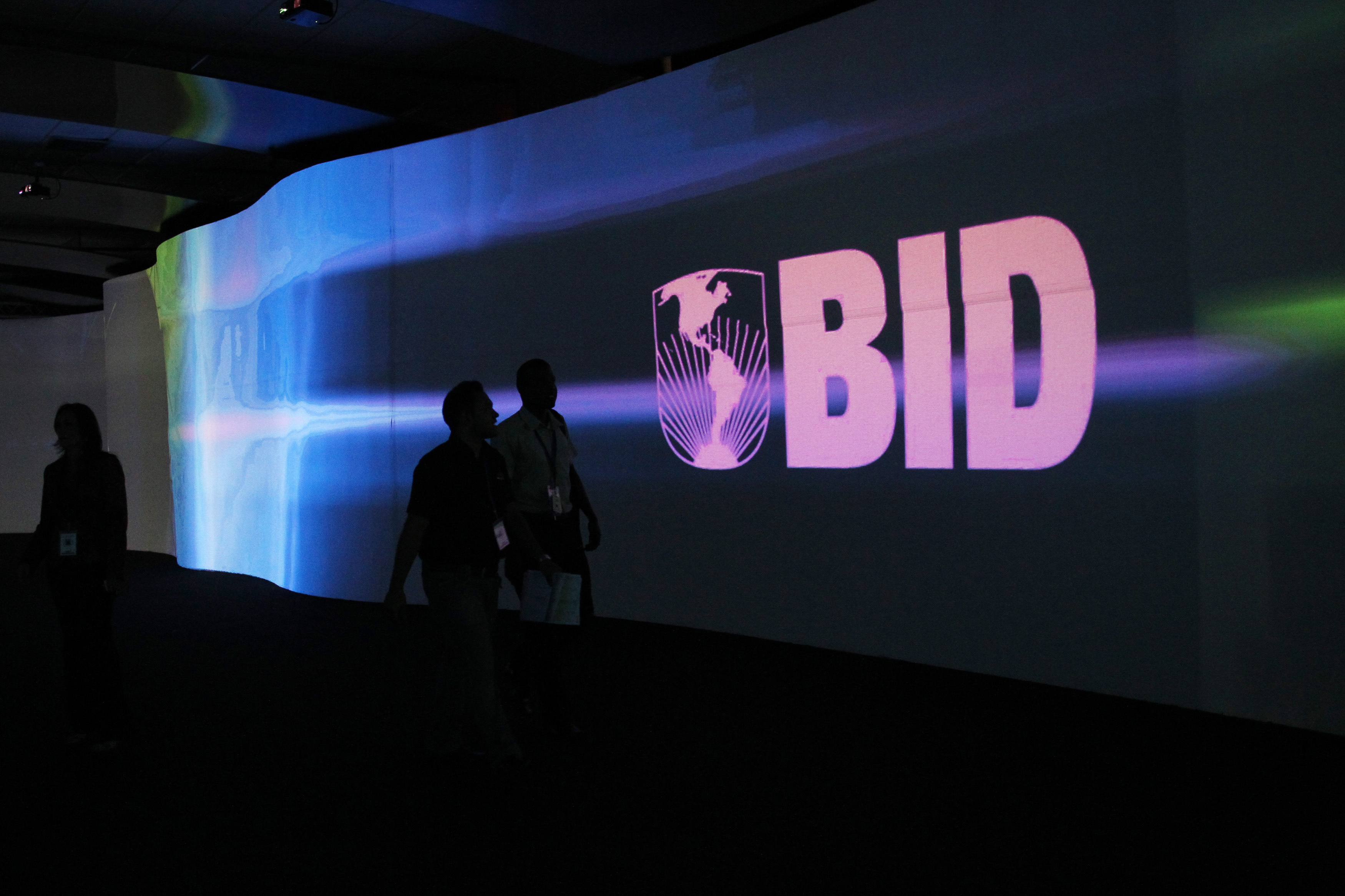 Visitors walk past a screen with the logo of Banco Interamericano de Desarrollo at the Atlapa Convention Center in Panama City