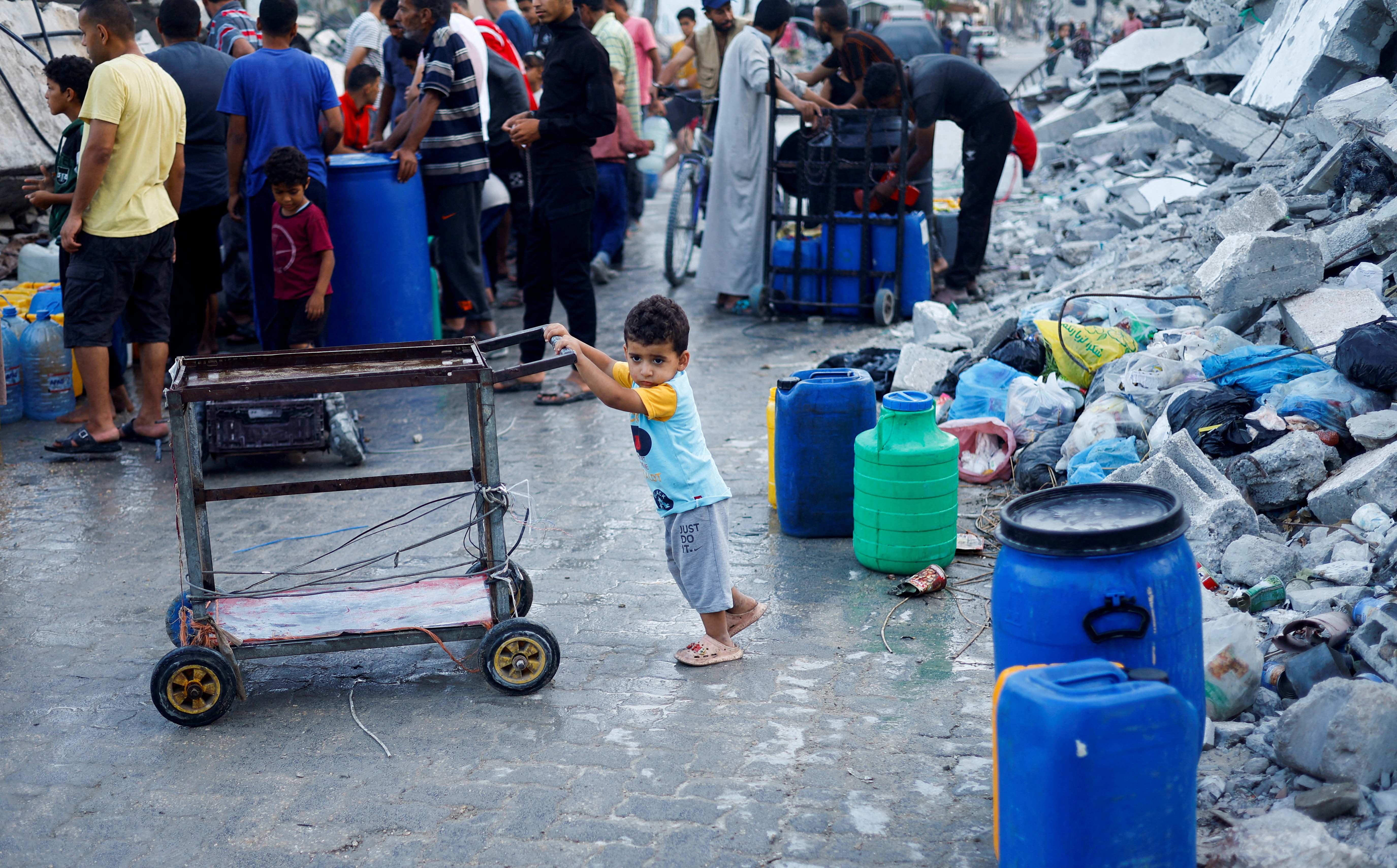 A Palestinian child stands next to water containers, amid the ongoing conflict between Israel and Hamas, in southern Gaza City, in the Gaza Strip