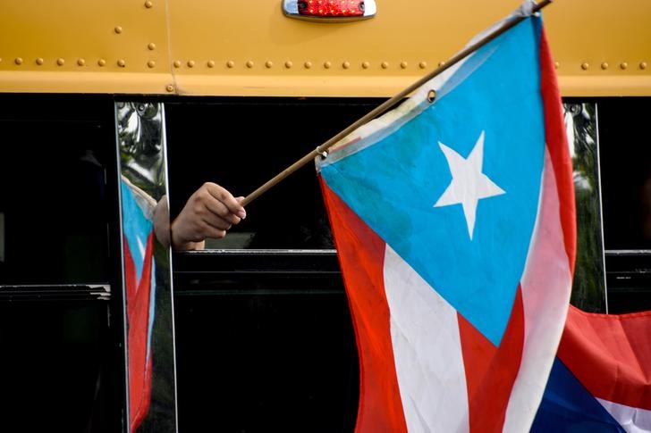 Demonstrators wave Puerto Rican flags out of a bus window during the national strike calling for the resignation of Governor Ricardo Rossello in San Juan