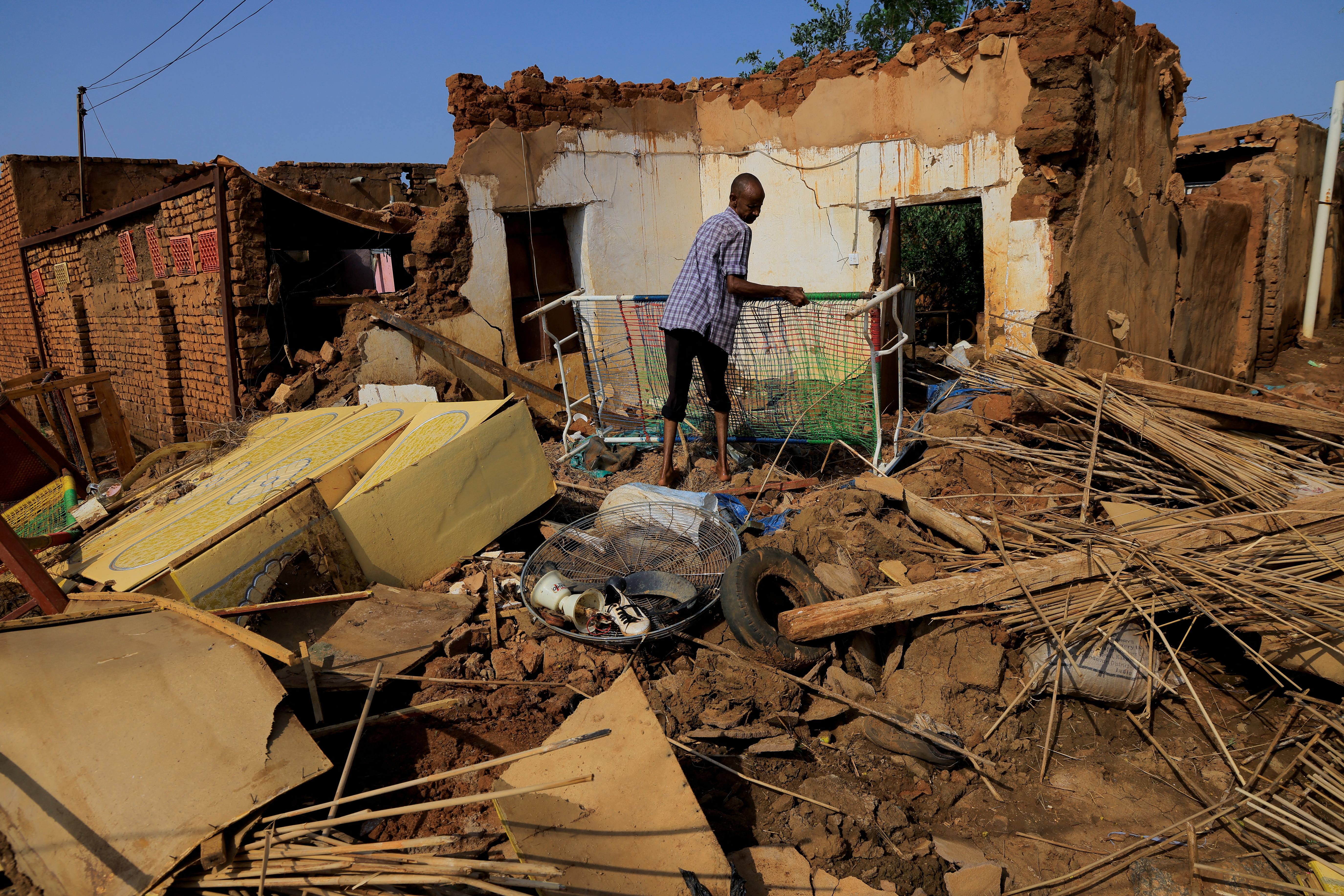 A man collects his belongings after sustaining water damage to his house during floods in Jazeera State