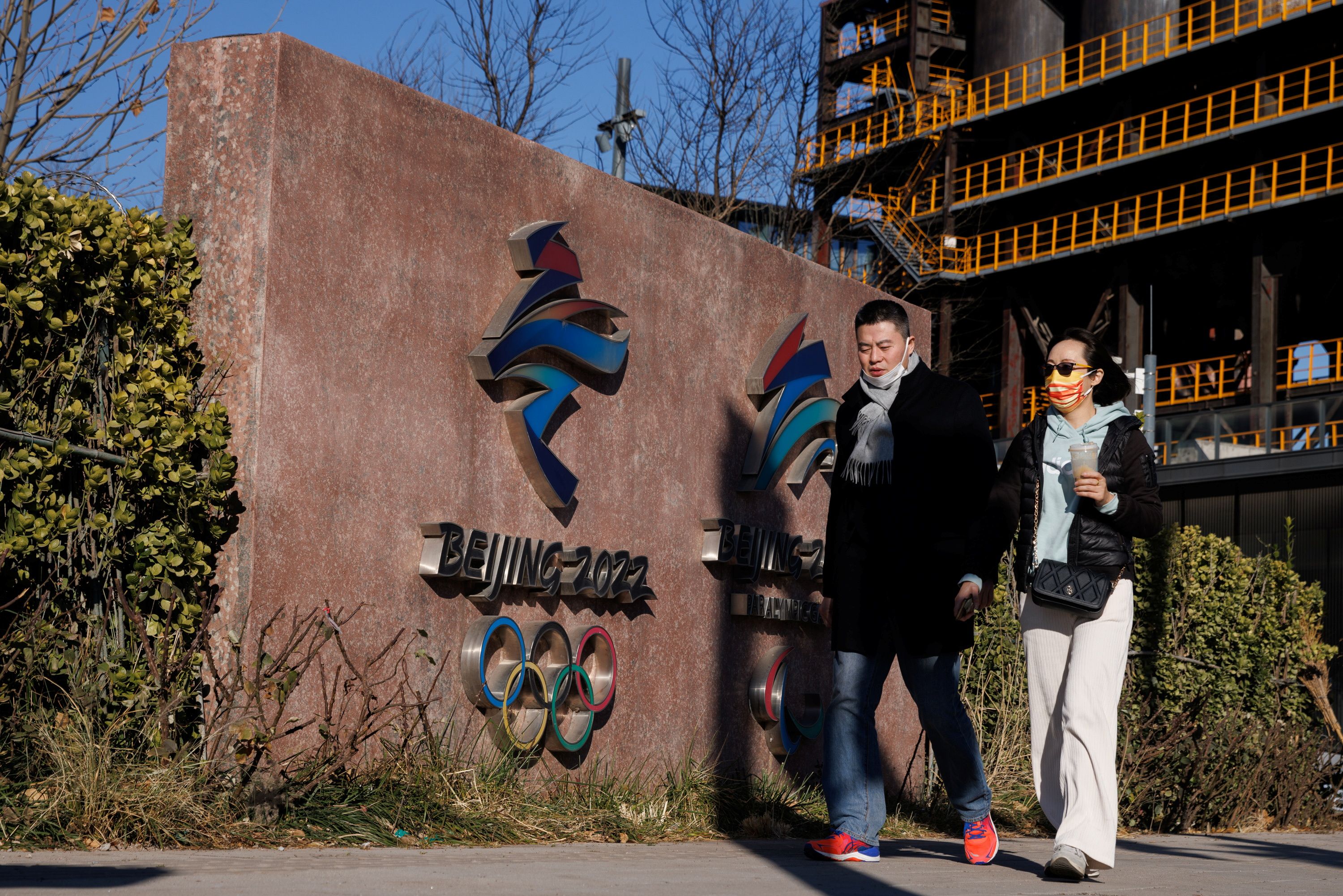 People walk past the headquarters of the Beijing Organising Committee for the 2022 Olympic and Paralympic Winter Games in Beijing