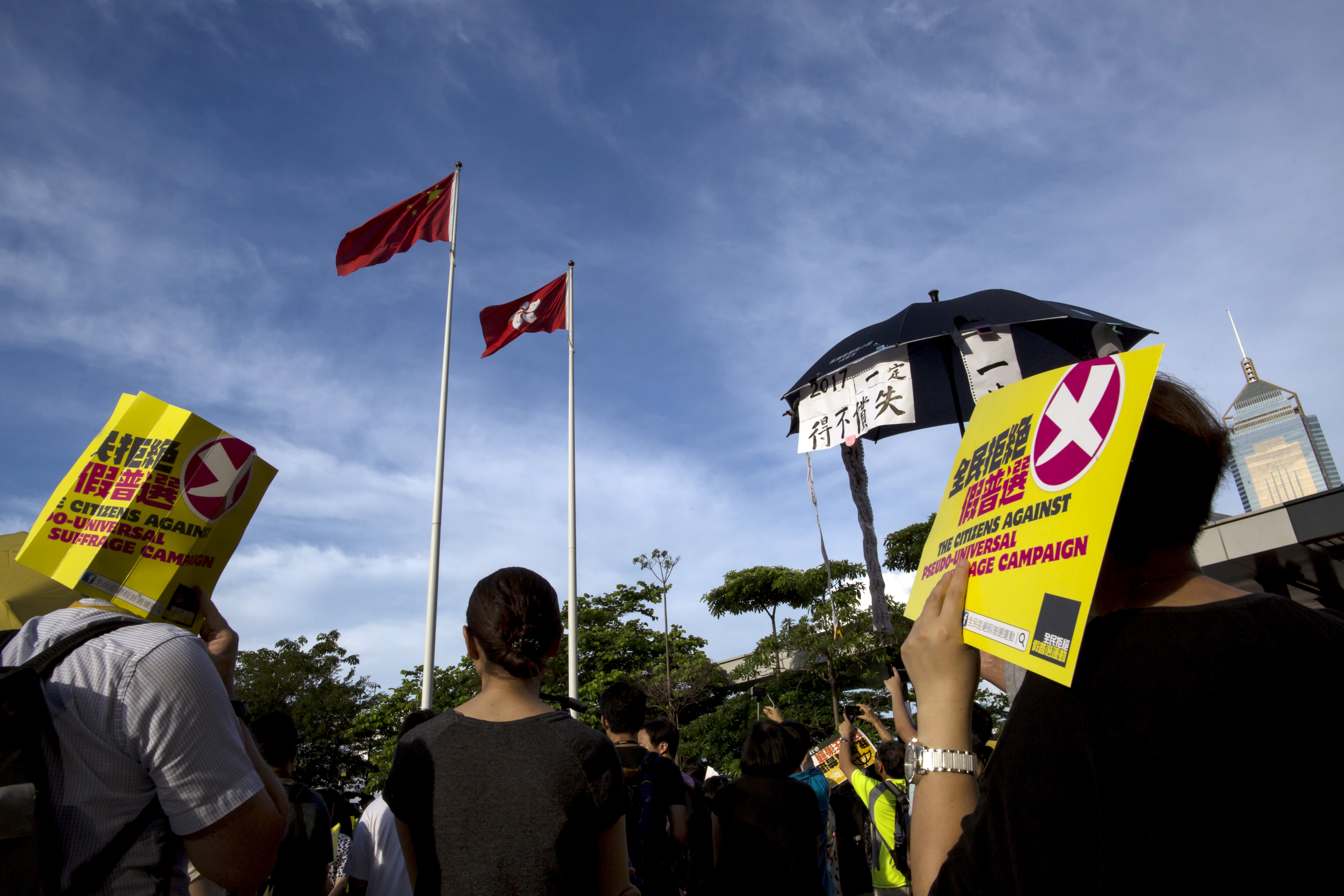 Pro-democracy protesters hold signs during a march under Hong Kong flags outside the Legislative Council building in Hong Kong, China