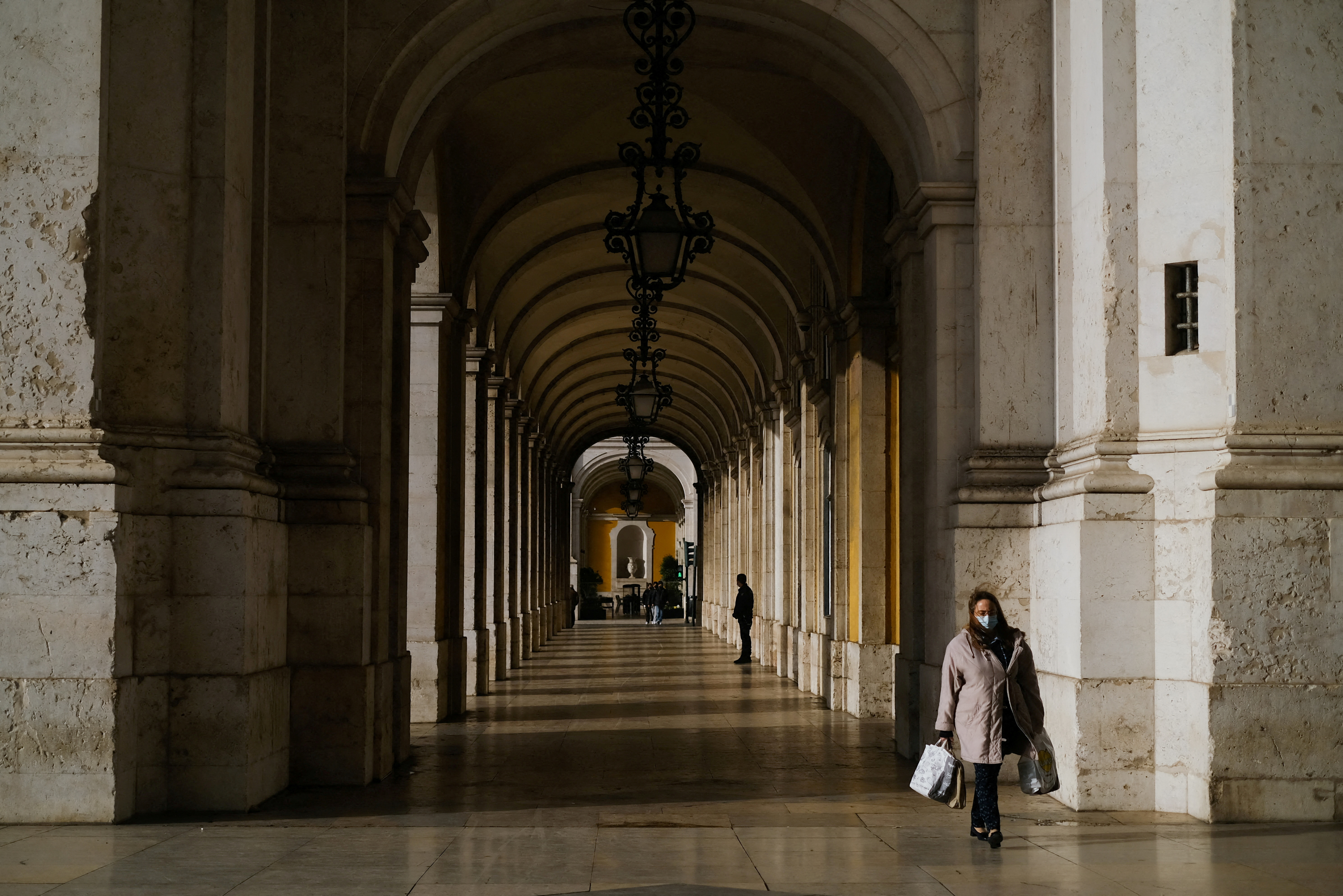 A woman wearing a protective masks walks in Terreiro do Paco, moments before a governmental news conference to announce new coronavirus disease (COVID-19) restrictions, in Lisbon, Portugal, December 21, 2021. REUTERS/Pedro Nunes