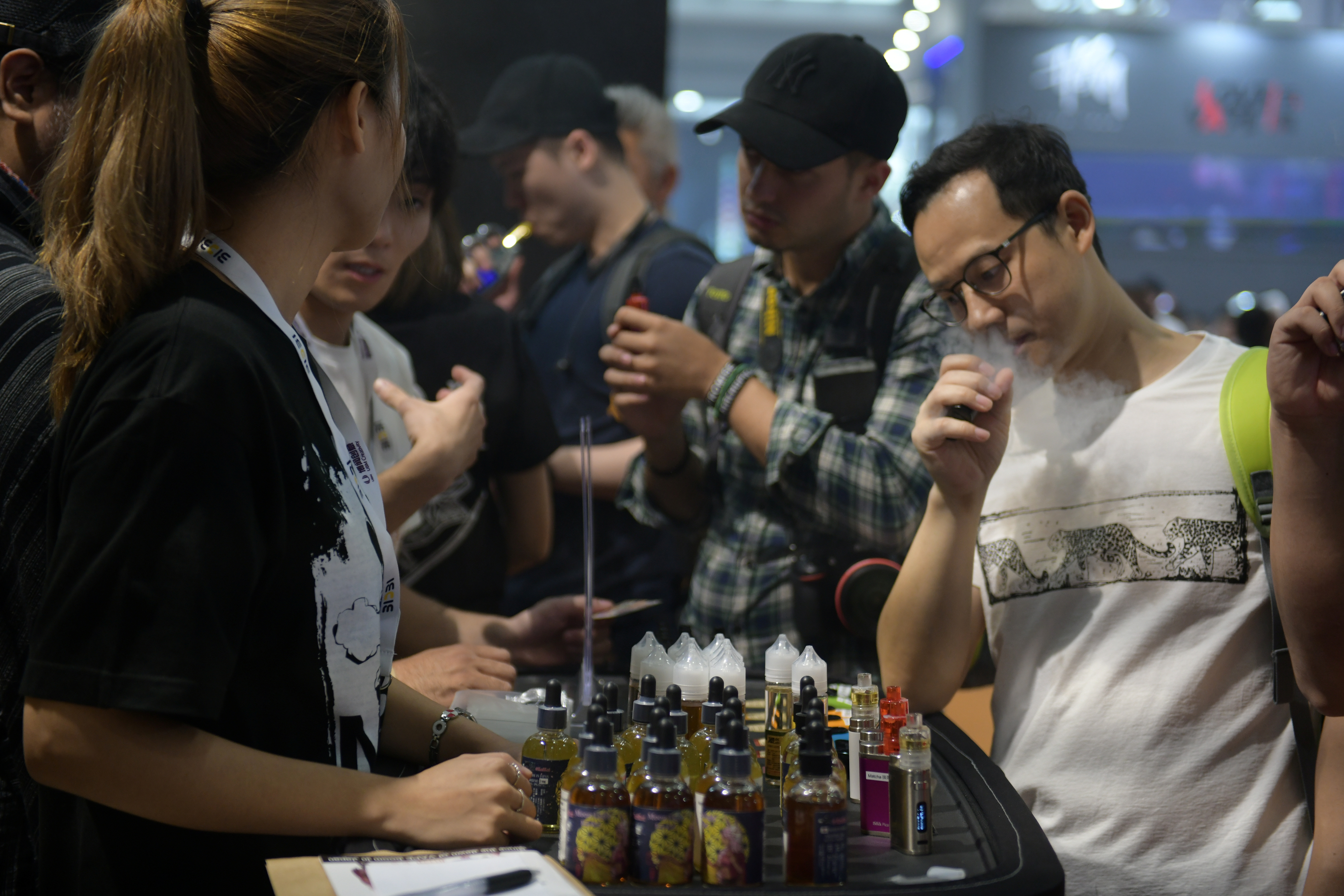 Visitors try out e-cigarette products at a booth during the eCig Expo (IECIE) in Shenzhen, Guangdong
