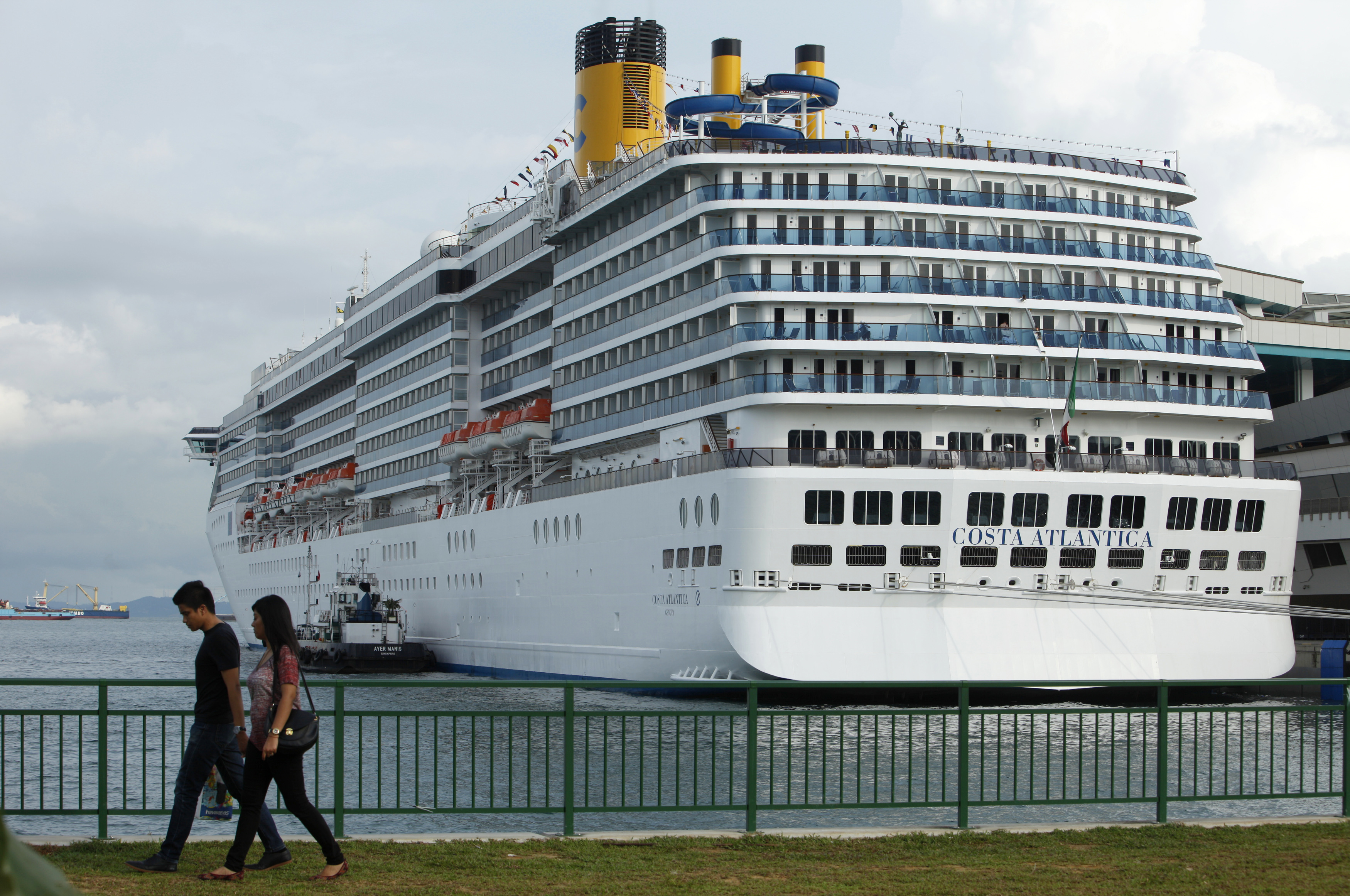 A couple walks past Carnival Asia's Costa Atlantica during its maiden call at the Marina Bay Cruise Center in Singapore