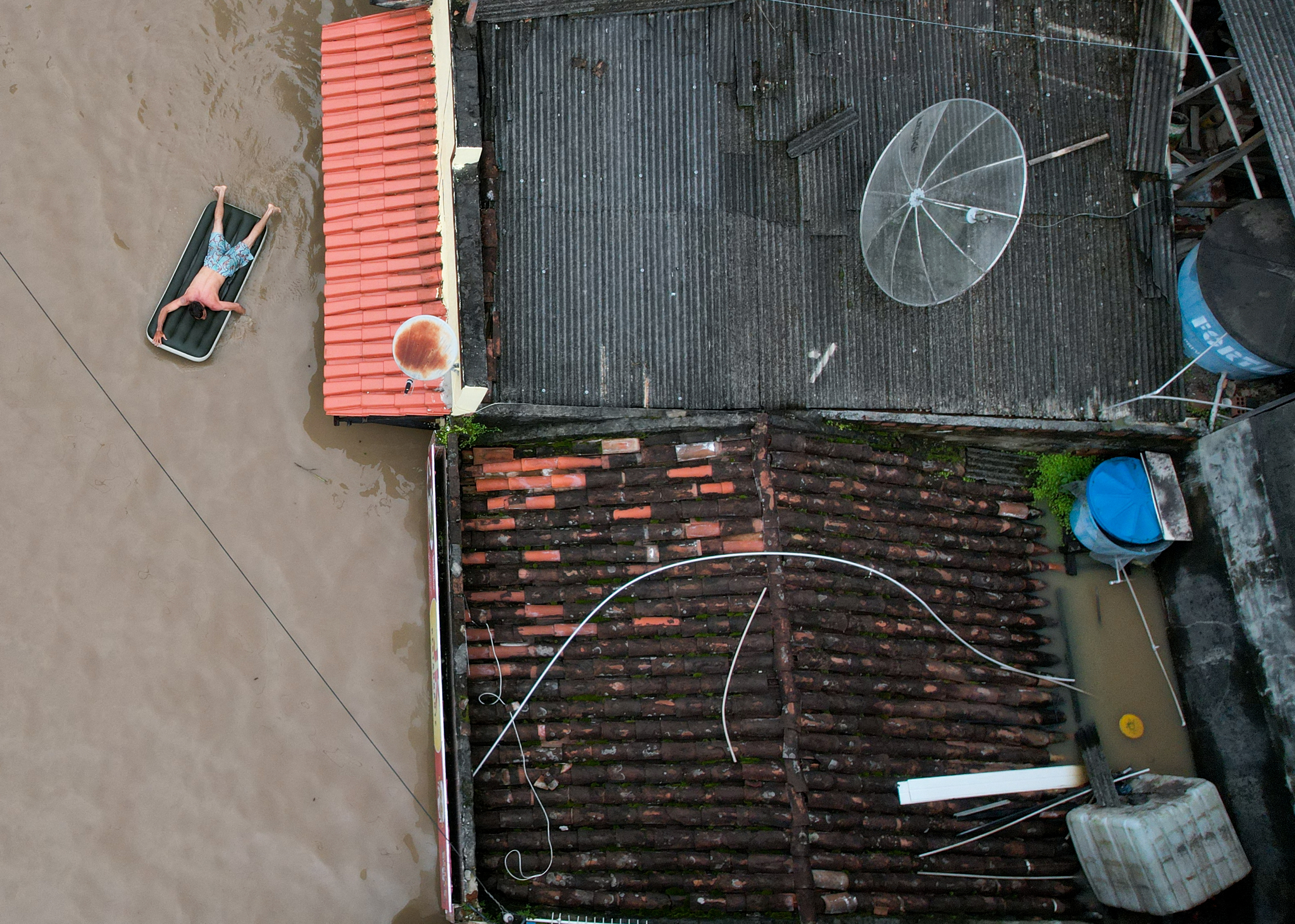 A man uses an inflatable mattress during flooding caused by the overflowing Cachoeira river in Itabuna, Bahia state, Brazil, December 26, 2021. Picture taken with a drone. REUTERS/Leonardo Benassatto