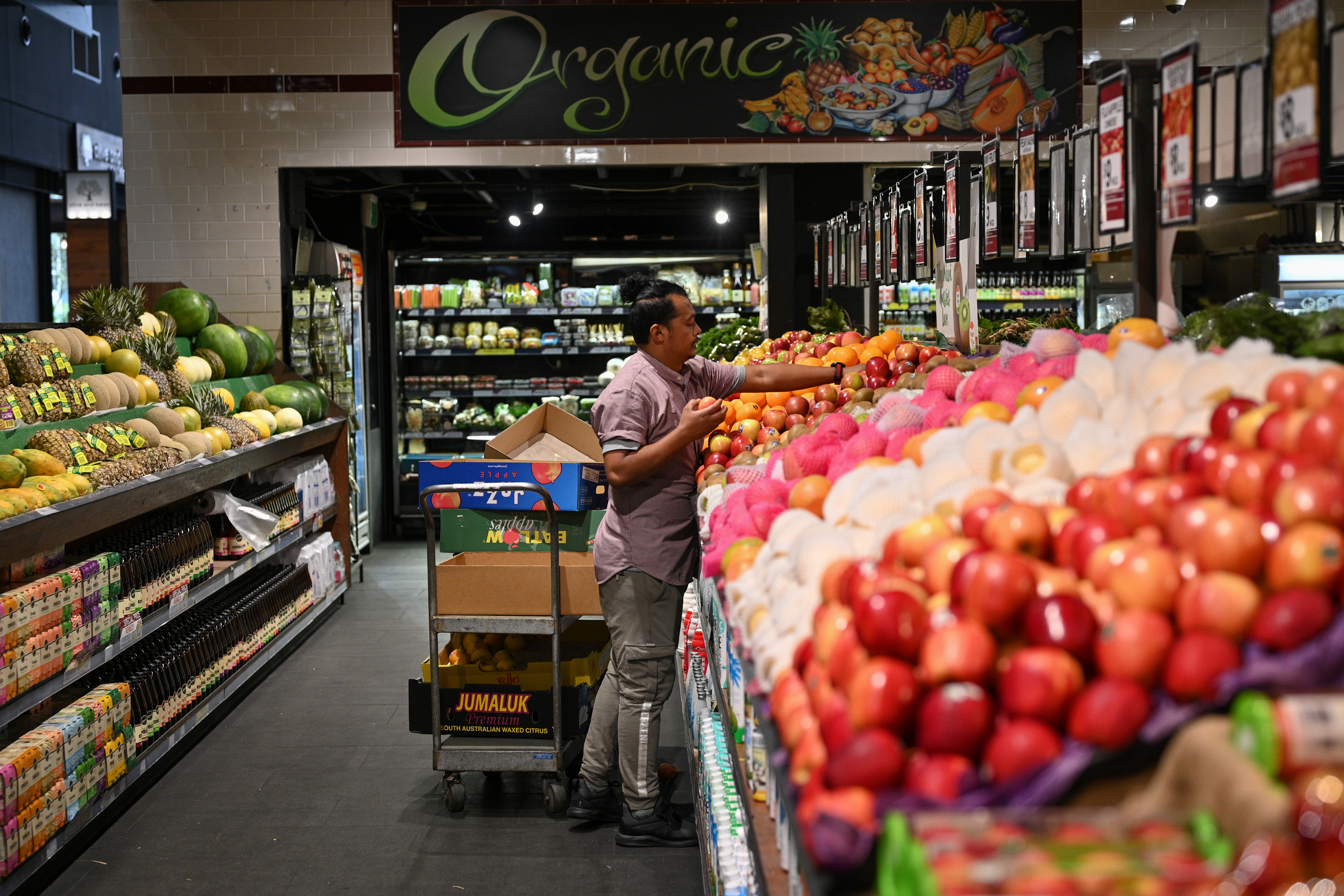 An employee stocks fruit at a specialty grocery store in Sydney