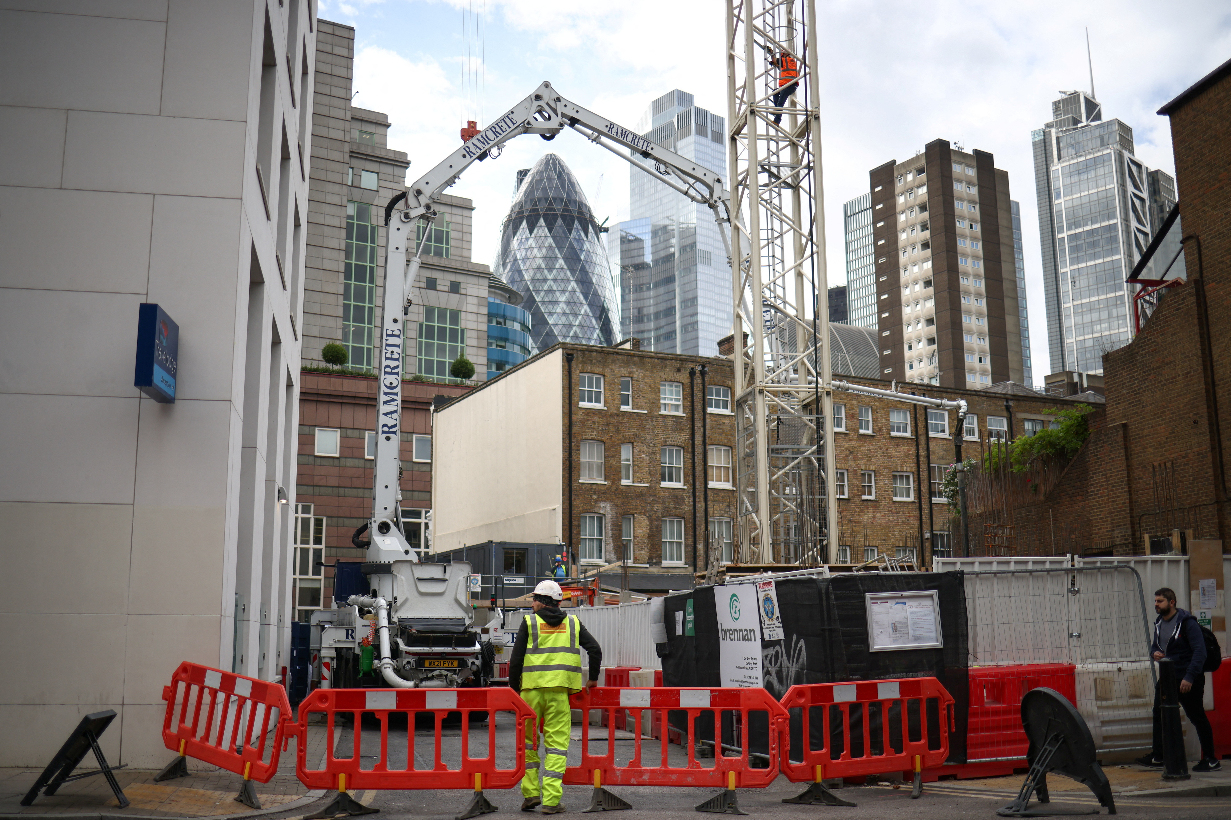 A construction worker moves barriers at a construction site, with the City of London financial district seen behind