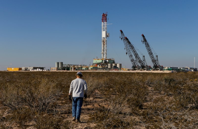 An oil worker walks towards a drill rig after placing ground monitoring equipment in the vicinity of the underground horizontal drill in Loving County