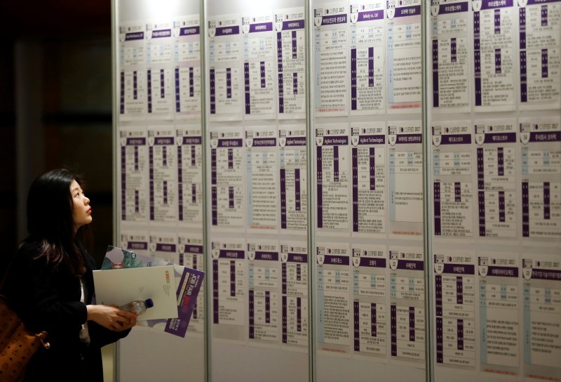 A woman looks at recruiting information during a job fair in Seoul
