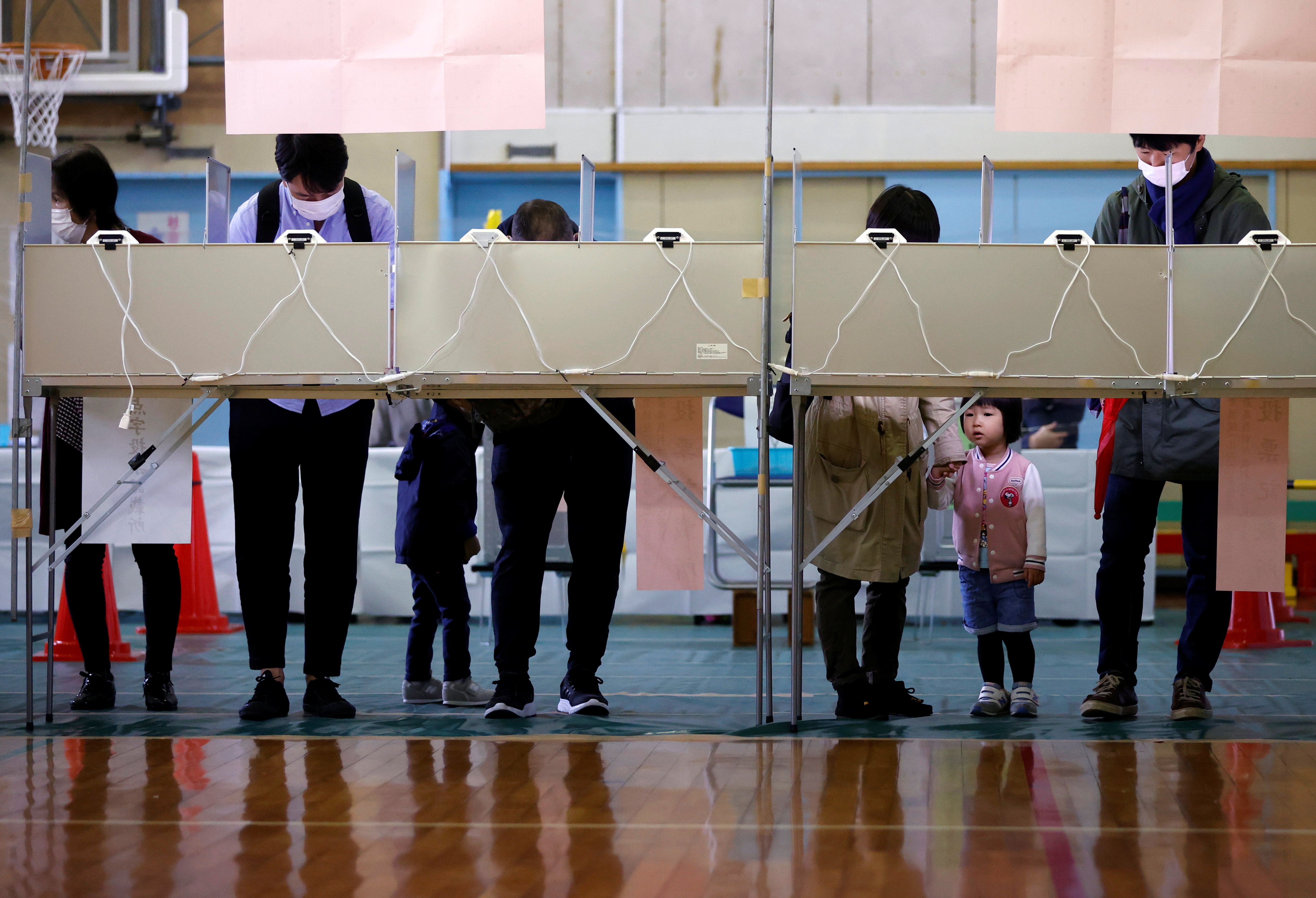 Voters prepare to cast their ballots in the lower house election at a polling station, amid the coronavirus disease (COVID-19) pandemic, in Tokyo