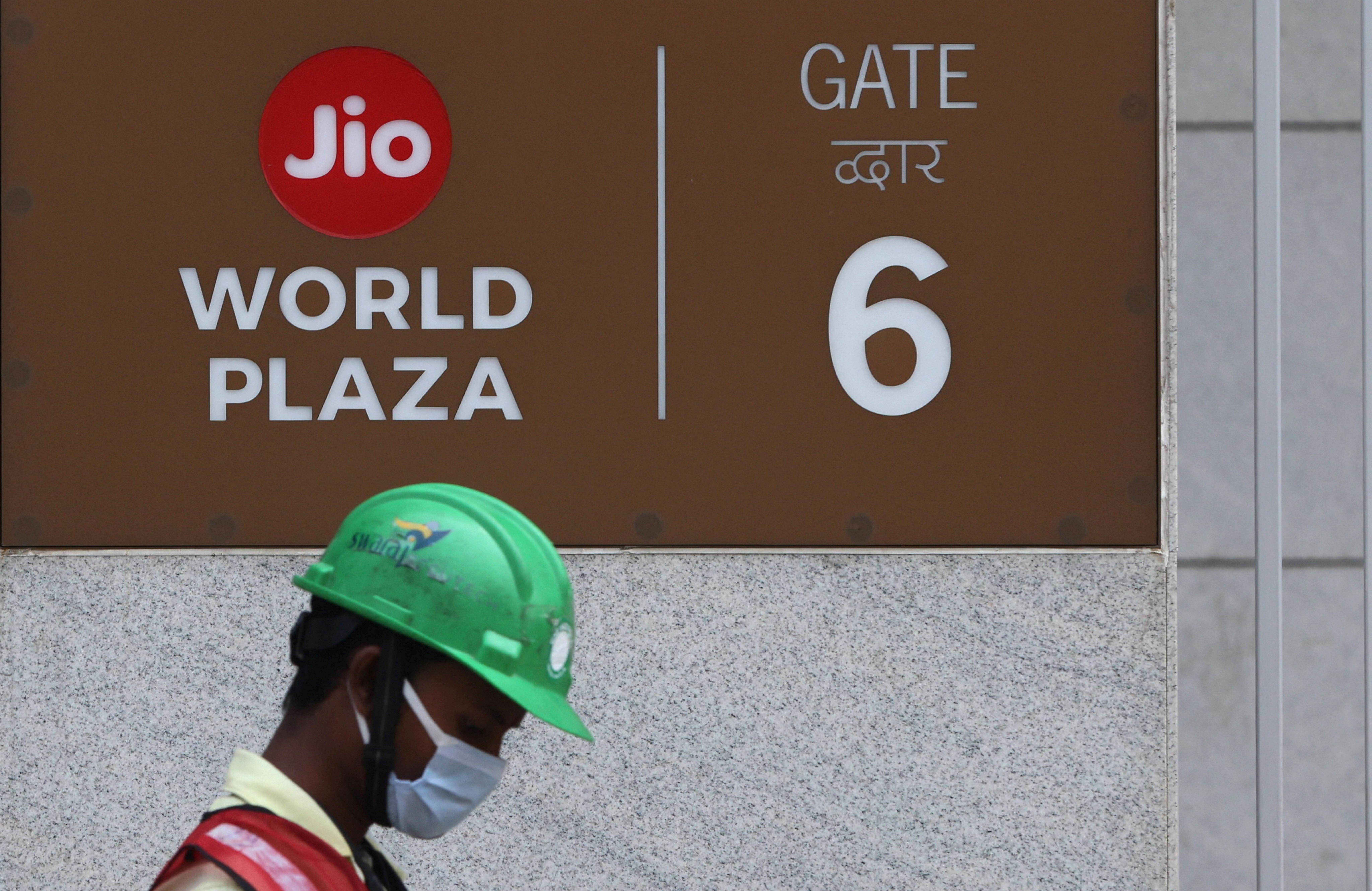 A construction worker walks past a gate of Reliance's Jio World Plaza in Mumbai