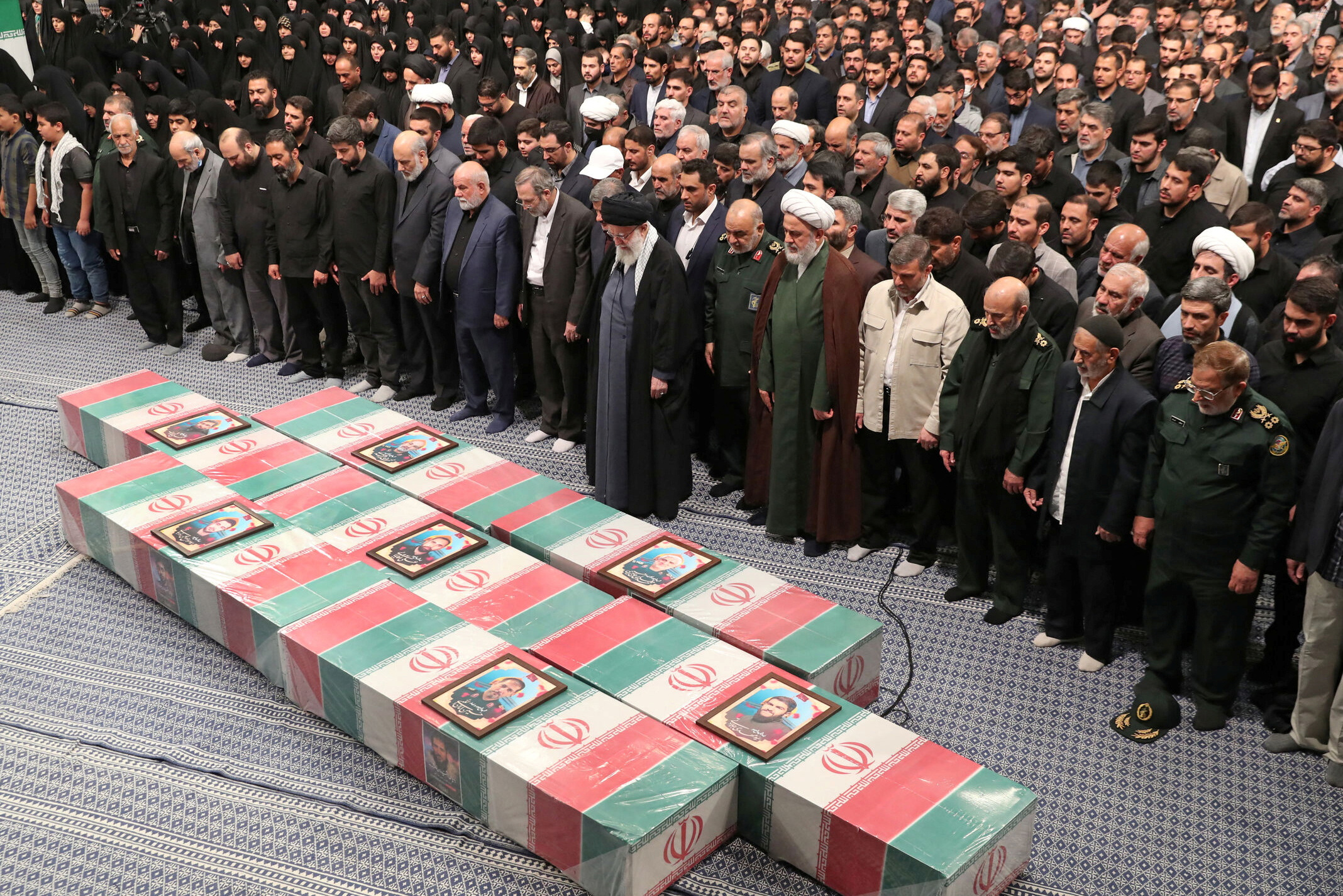Iran's Supreme Leader, Ayatollah Ali Khamenei prays next to the coffins of members of the Islamic Revolutionary Guard Corps, in Tehran
