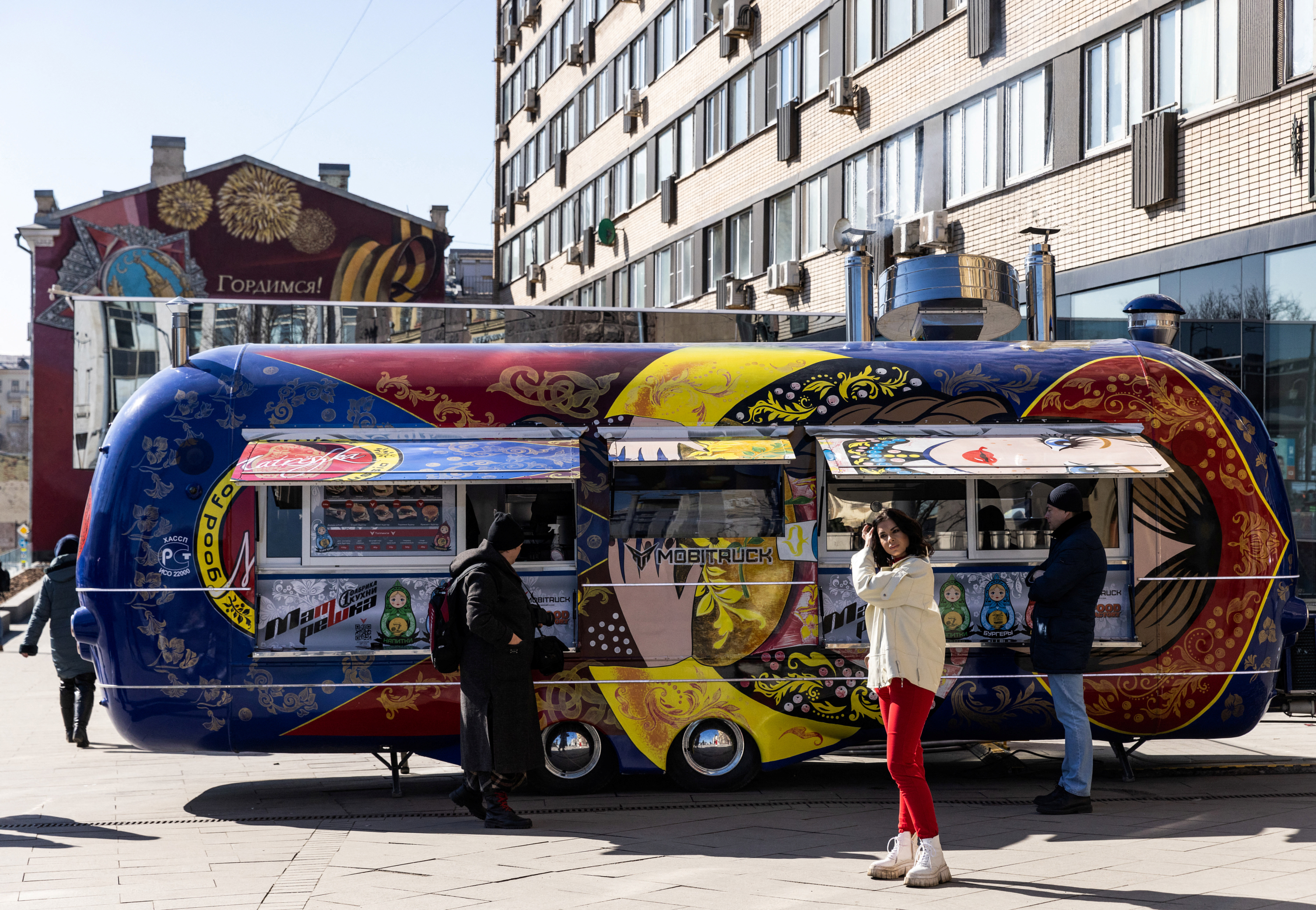 A woman looks on near a food truck painted as a Russian matryoshka doll and set near the closed oldest McDonald's restaurant in Moscow
