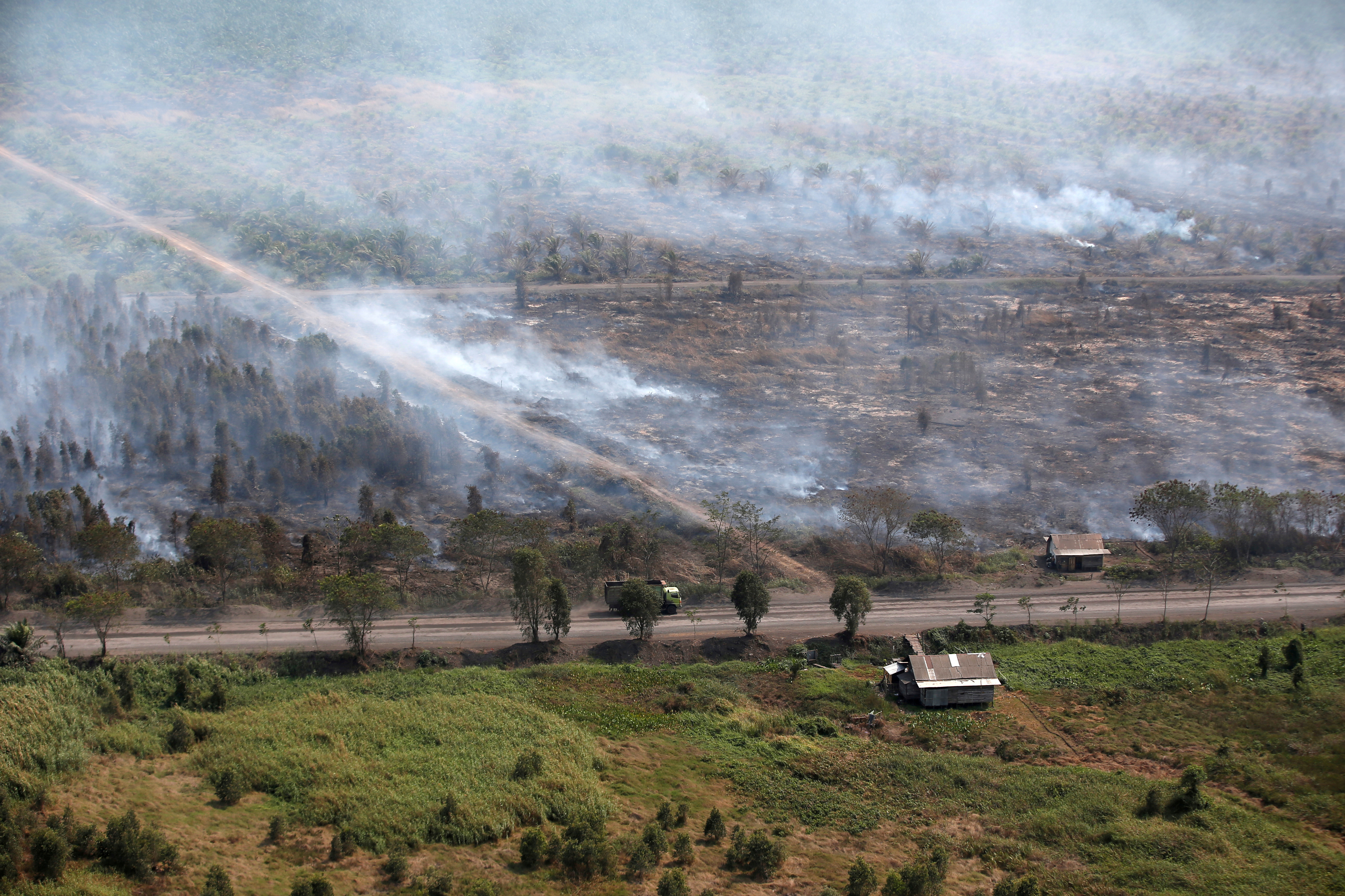 Kebakaran hutan di dekat Banjarmasin di provinsi Kalimantan Selatan menunjukkan rumah-rumah kayu yang dipenuhi asap.