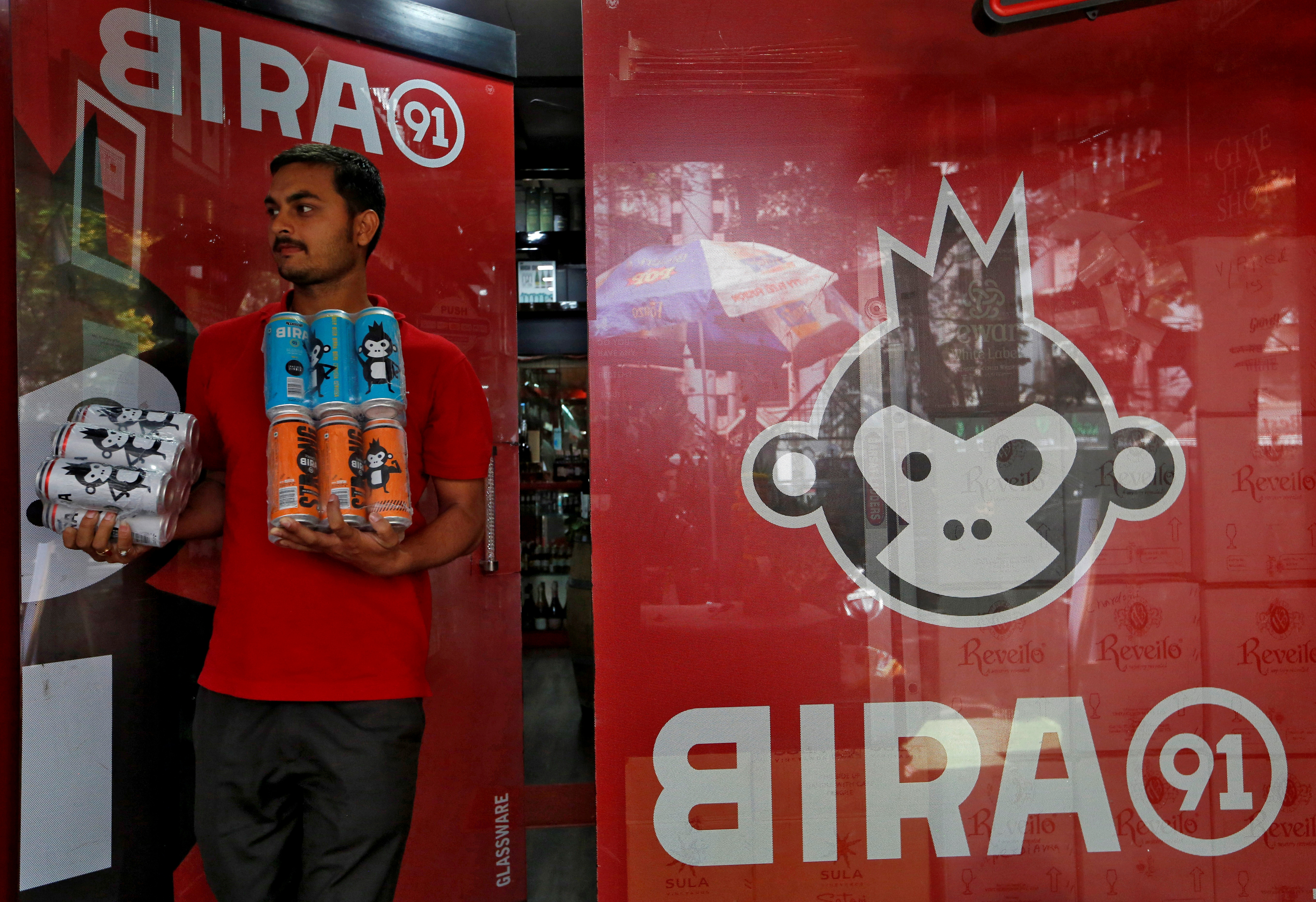 An employee carries Bira beer cans to deliver them to a customer at a liquor store in Mumbai