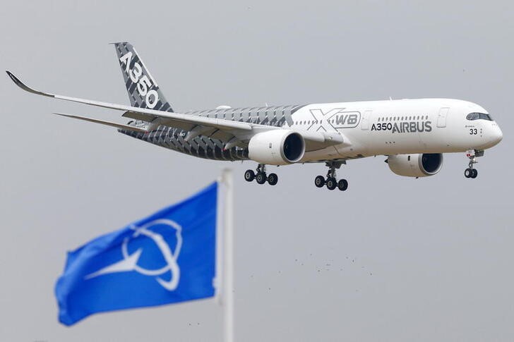 An Airbus A350 jetliner flies over Boeing flags as it lands after a flying display during the 51st Paris Air Show at Le Bourget airport near Paris