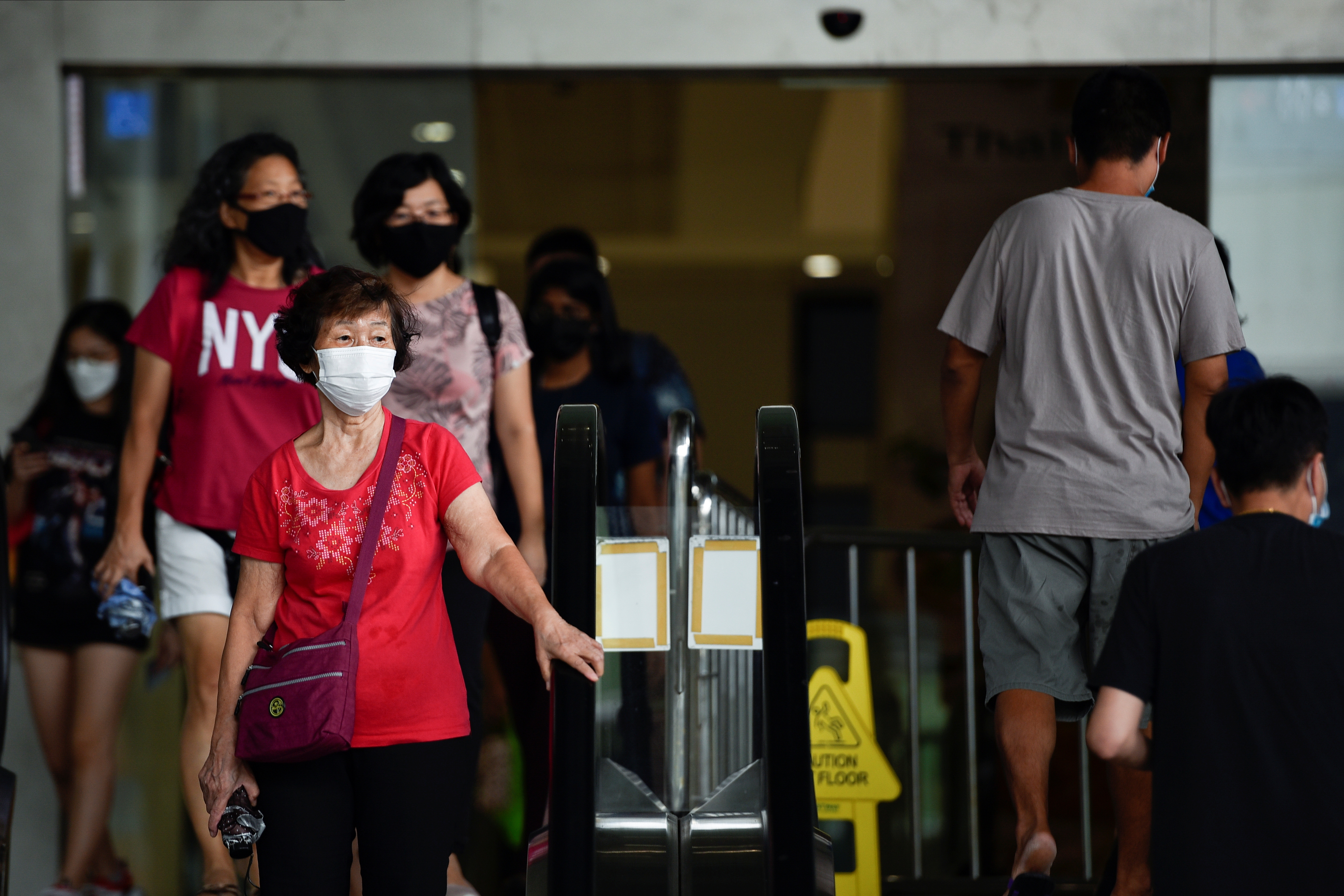 People wearing face masks walk out of a mall amid the coronavirus disease (COVID-19) outbreak in Singapore