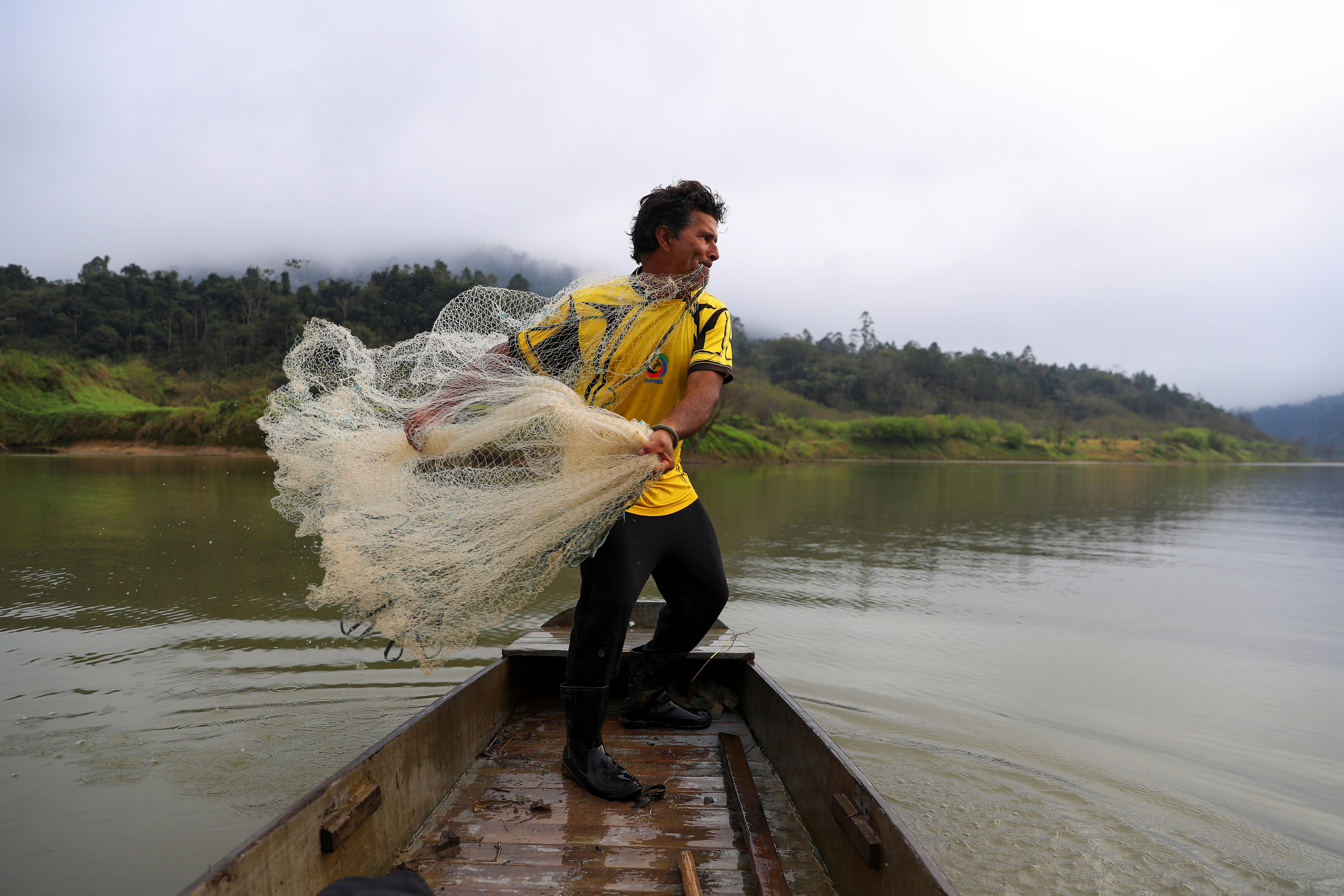 An indigenous fisherman throws a net from his canoe in Xokleng Laklano indigenous land