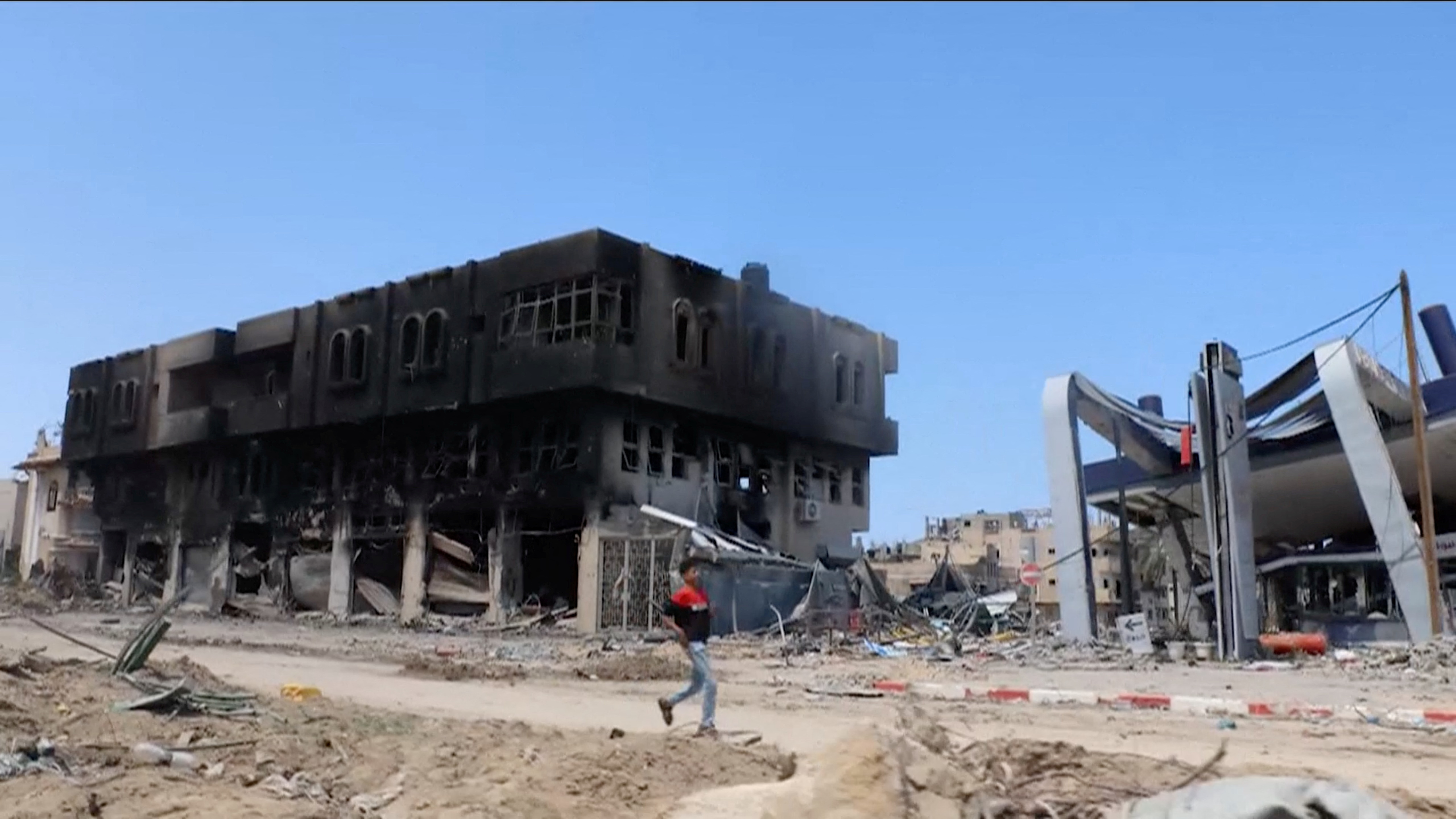 A person walks past destroyed buildings in Khan Younis