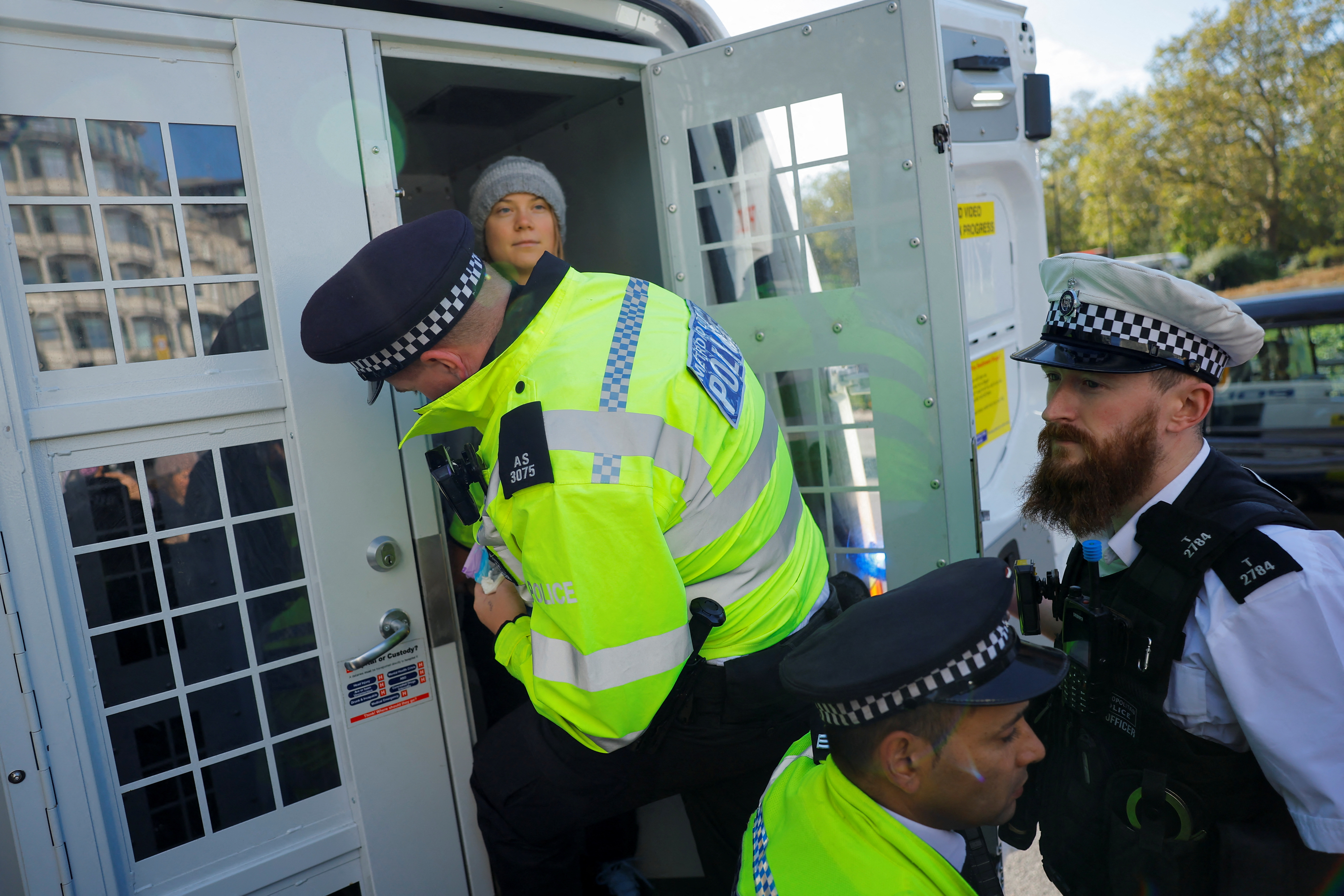 A police officer detains a climate activist after she sprayed