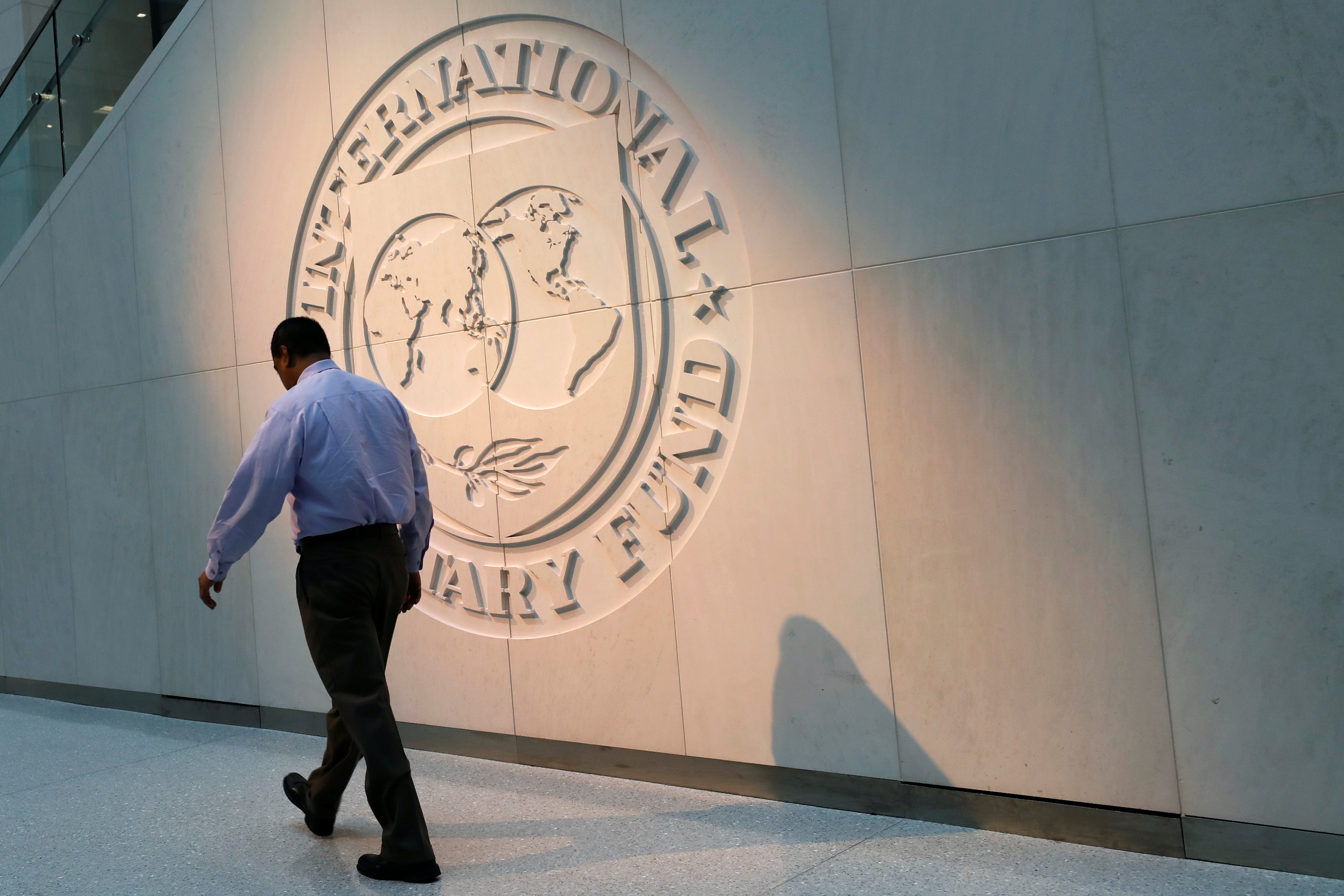 Man walks past IMF logo at headquarters in Washington
