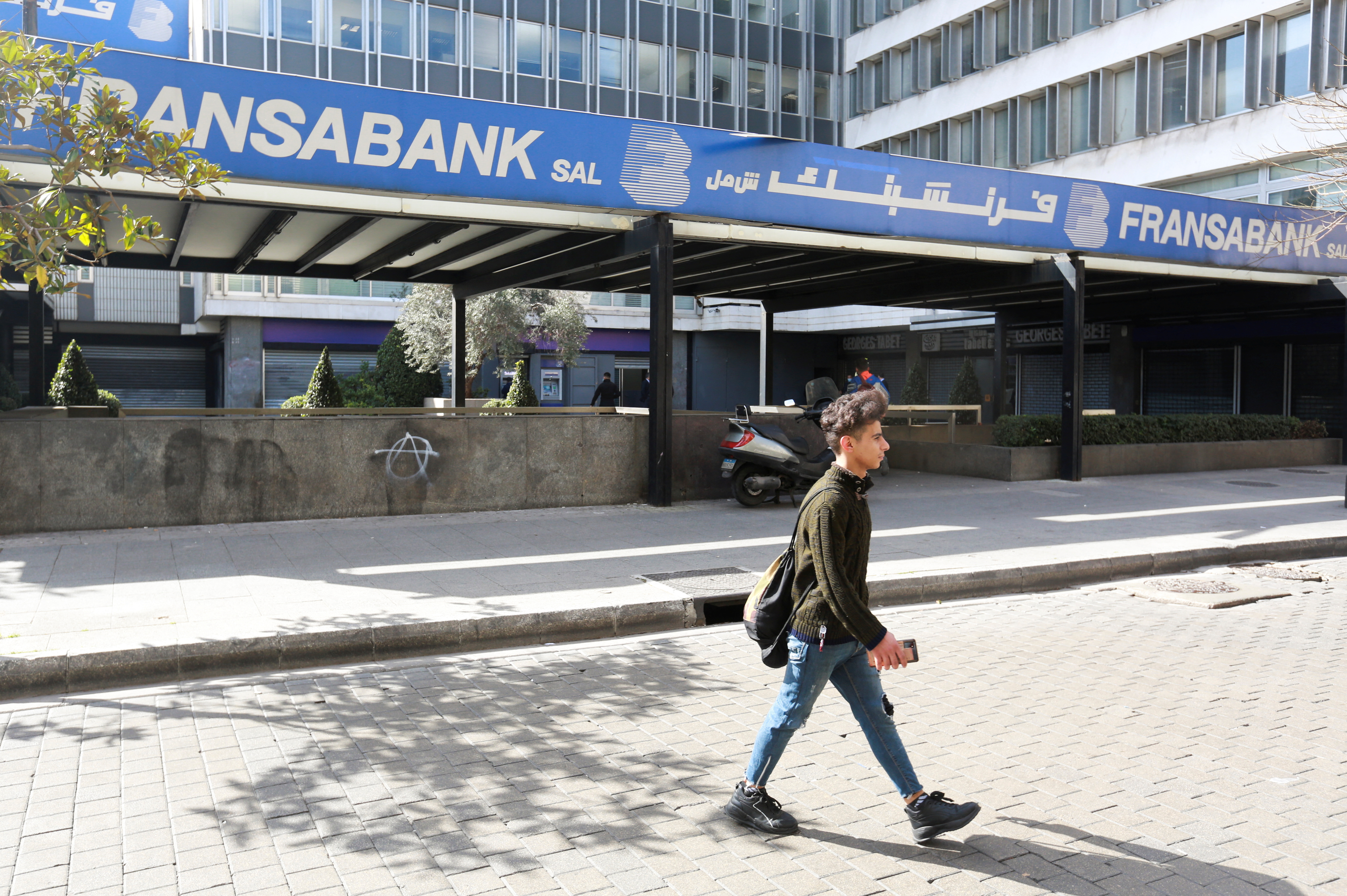 A man walks near a branch of Fransabank in Beirut