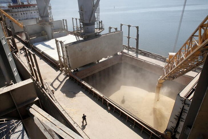 A dockyard worker watches on as barley grain is poured into a ship in Nikolaev