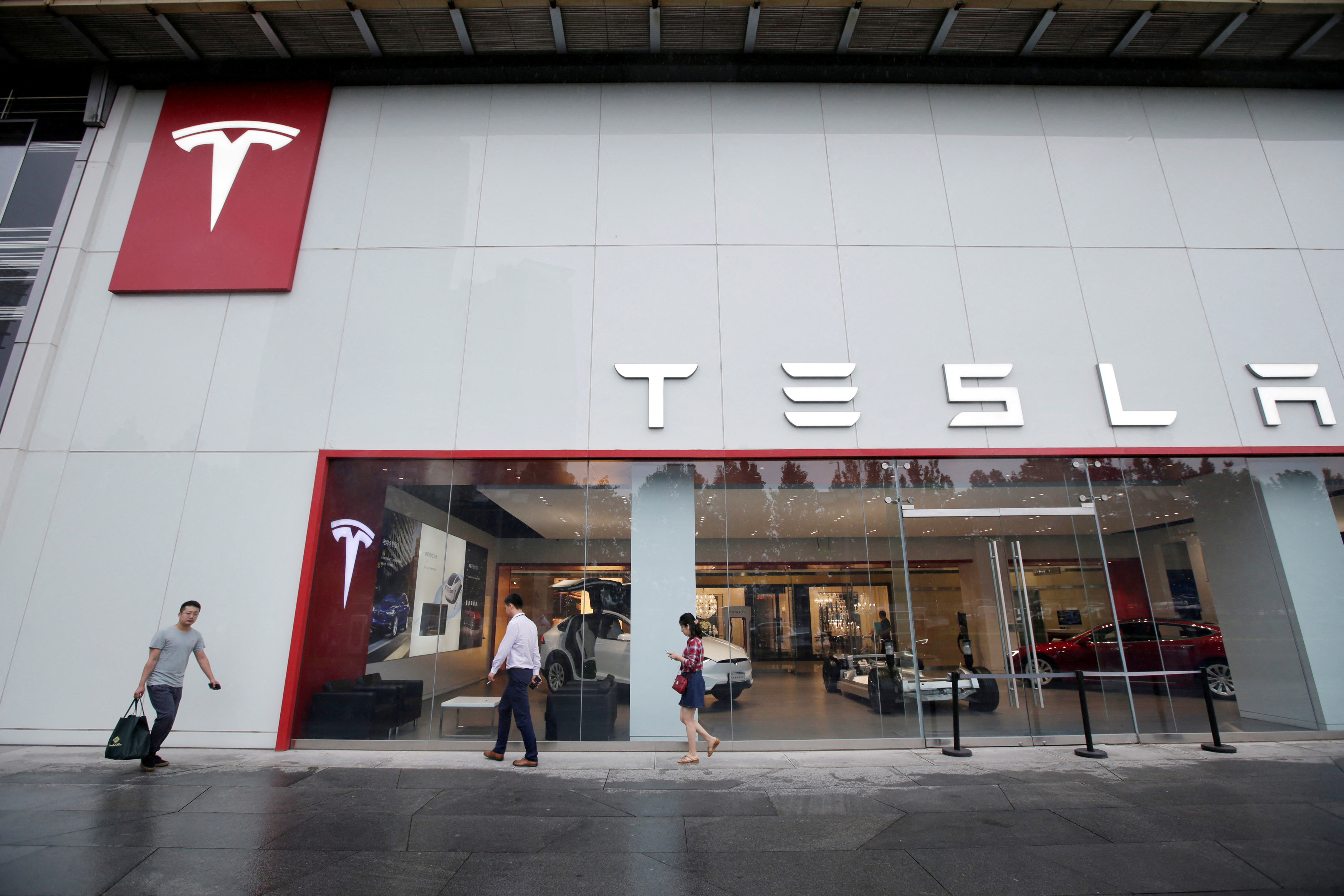 People walk past a showroom outside Tesla China headquarters in Beijing