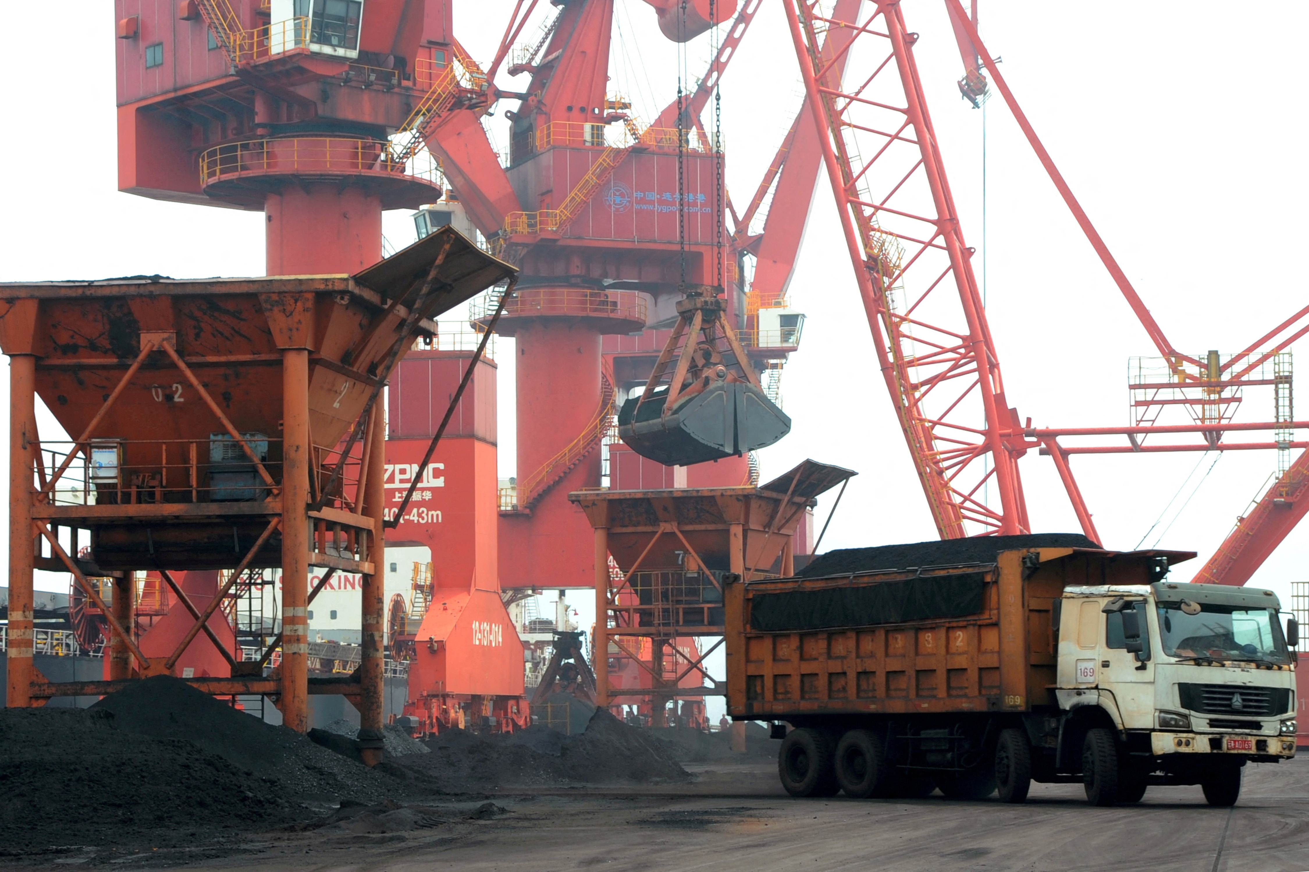 Imported coal is seen lifted by cranes from a coal cargo ship onto a truck at a port in Lianyungang, Jiangsu