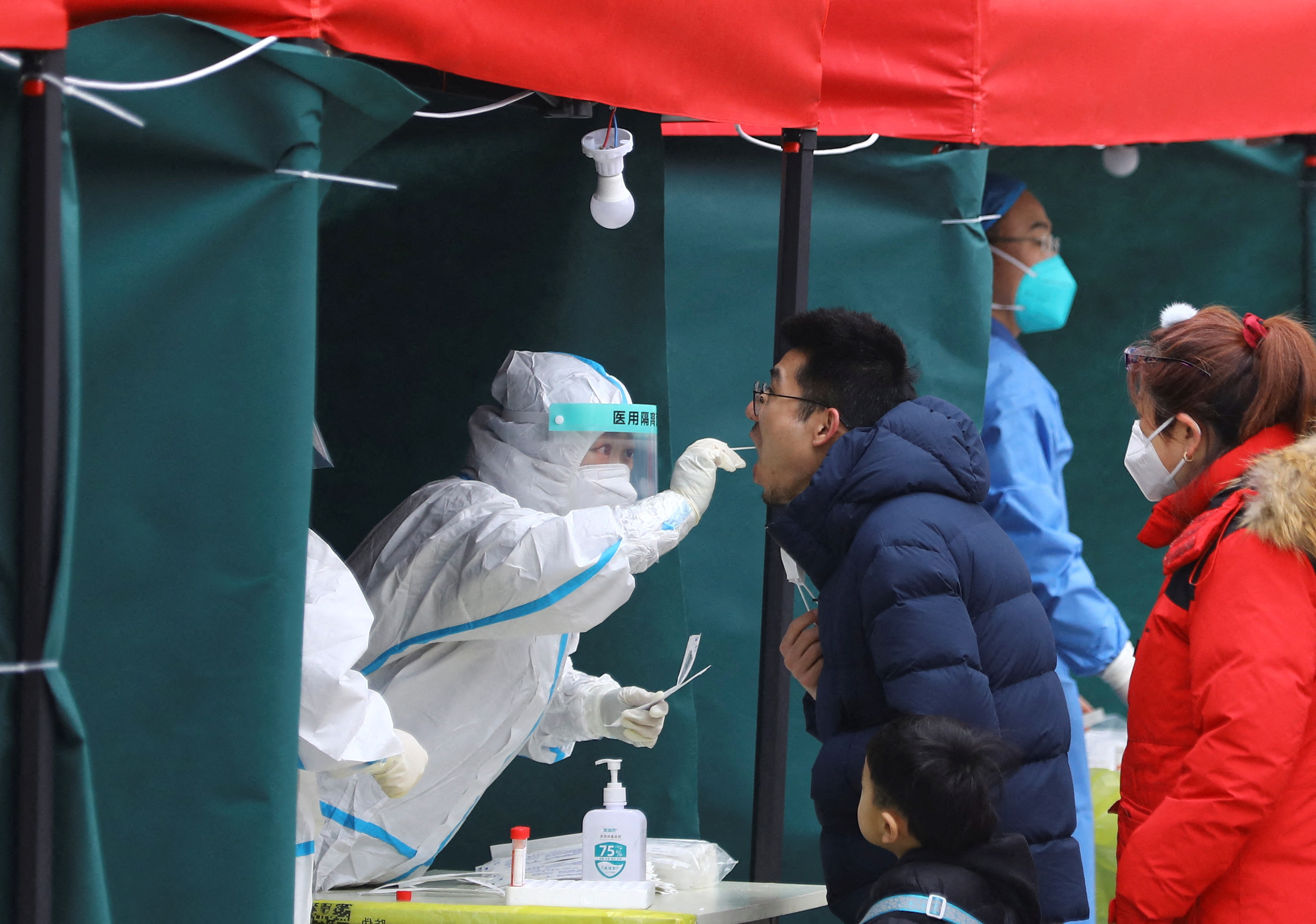 Medical worker collects a swab sample from a resident at a makeshift nucleic acid testing site at a residential compound in Beijing