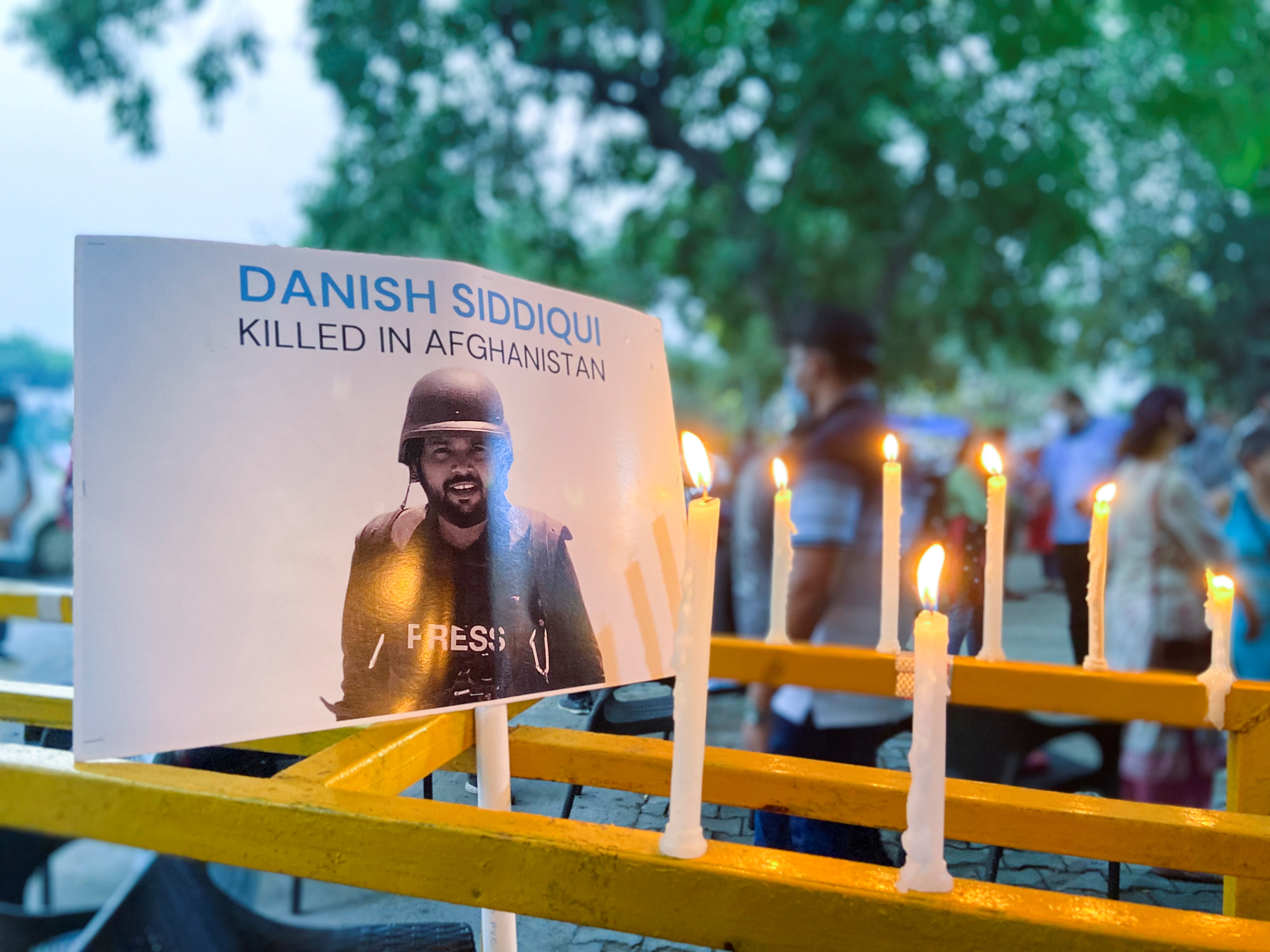 Candles are seen lit next to a photograph of Reuters journalist Danish Siddiqui after he was killed while covering a clash between Afghan security forces and Taliban fighters near a border crossing with Pakistan, outside Press Club in New Delhi