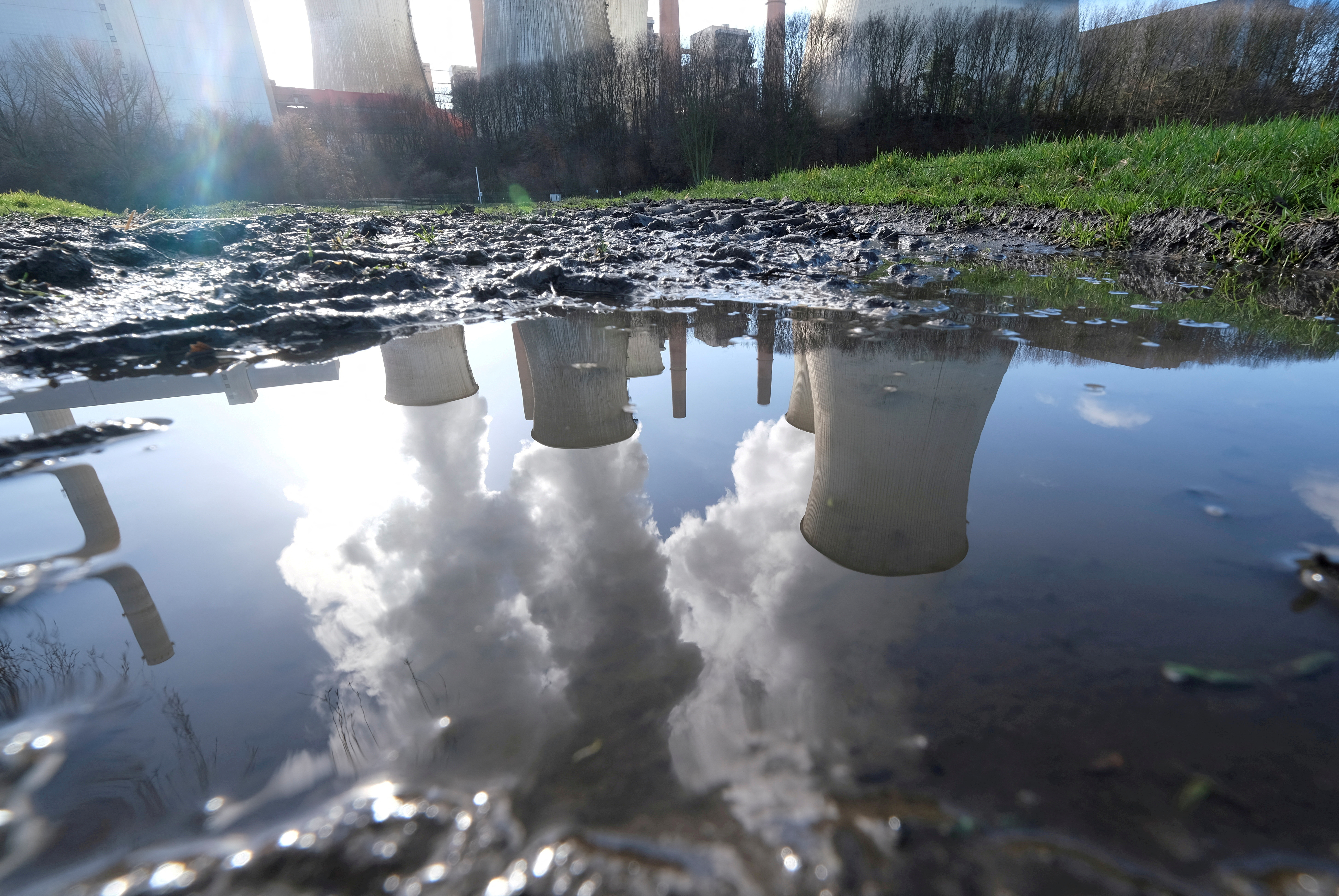 The lignite (brown coal) power plant complex of German energy supplier and utility RWE is reflected in a puddle in Neurath
