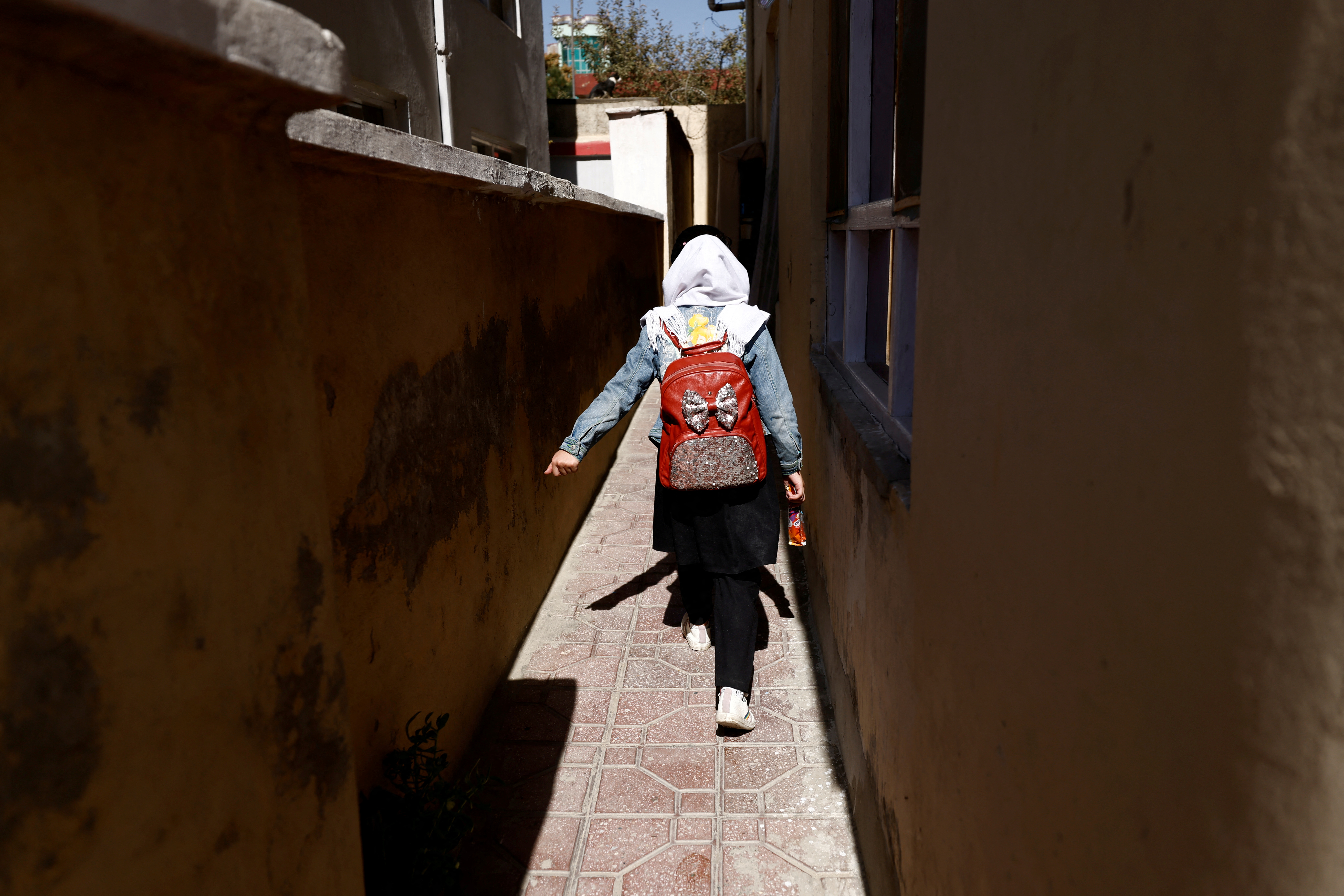 A school student walks back from school through an alleyway near her home in Kabul